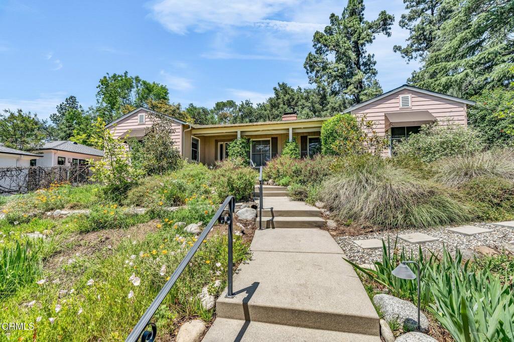 Nestled in the foothills of Altadena near scenic hiking and nature trails, this updated traditional home blends timeless charm with a modern open layout. Originally designed by Robert E. Williams--an early partner in the notable firm Train & Williams--and first built by W. E. G. Saunders, the home offers both architectural significance and everyday comfort. At its heart is a dramatic great room with vaulted ceilings, a fireplace, French doors to the backyard, and large windows that fill the space with natural light. The chef's kitchen features a center island, breakfast bar, stainless steel appliances, and granite counters. Additional highlights include a formal living room with wall-to-wall bookcases and fireplace, an oversized dining room, and a spacious primary suite with walk-in closet, spa tub, and travertine finishes. Two more generously sized bedrooms and 1.5 additional baths offer flexibility for guests or work-from-home. Hardwood floors, crown molding, recessed lighting, and thoughtful updates run throughout. A finished 550 sq ft two-car garage includes an EV charger. Surrounded by mature trees with views of the mountains, this home is a peaceful retreat in a coveted foothill location.