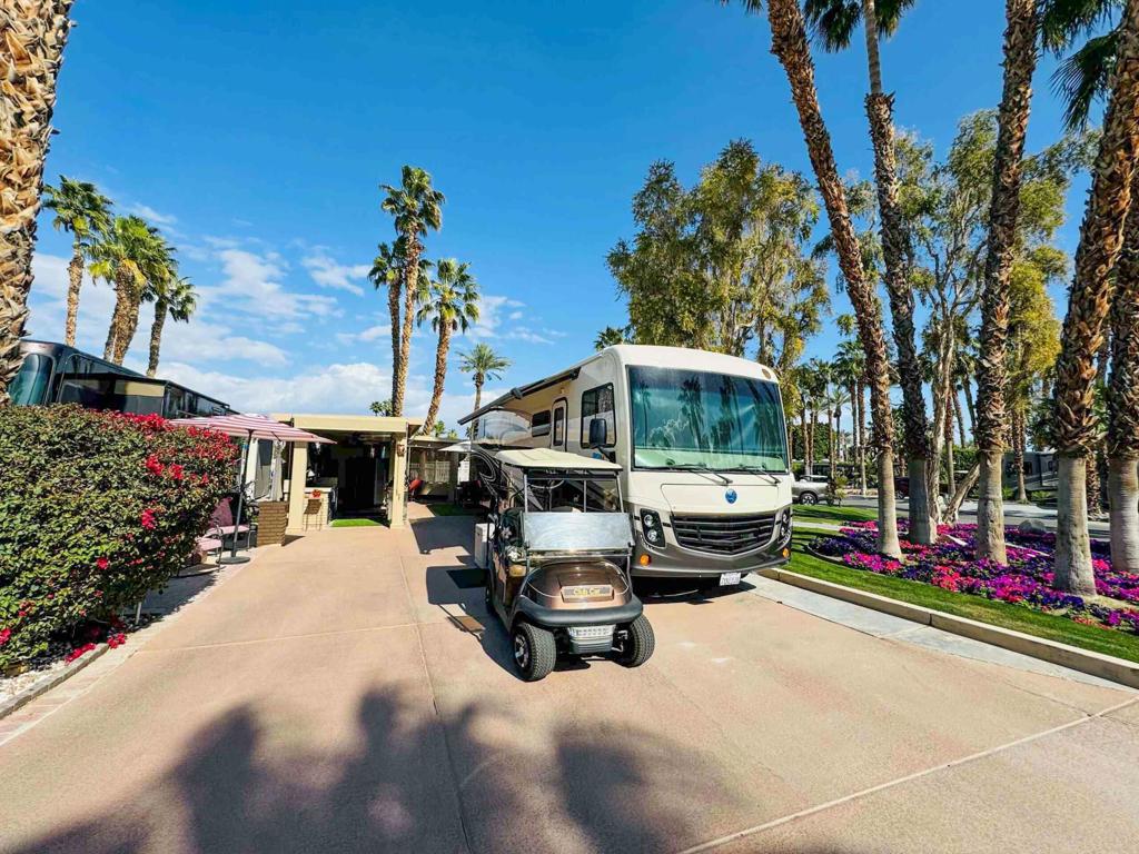 Start your morning with coffee under your private pergola, featuring an Aluma Wood shade structure and custom European shades, while savoring the serenity of this exceptional corner lot in Phase 2. Just steps from the pool, hot tub, laundry, and shower facilities, this rare gem combines luxury, privacy, and convenience in one inviting retreat. Enclosed by a tall ficus hedge maintained by the HOA, the patio dining area offers a secluded space perfect for relaxing or entertaining friends.This outdoor oasis boasts a fully equipped kitchen with granite tile countertops, a cooktop electric stove/oven, refrigerator, dishwasher, stainless steel sink, garbage disposal, and instant water heater. Ample storage is provided by a 6-foot Kobalt pantry, matching countertop units, and a stainless-steel storage cart. The space is furnished with a large table, two swivel chairs, four Sunbrella-upholstered chairs, and a large umbrella, ensuring style and comfort. A 65' smart TV mounted on a rolling storage cart completes this luxurious and functional retreat, making it perfect for enjoying the best of luxury RV living.‍