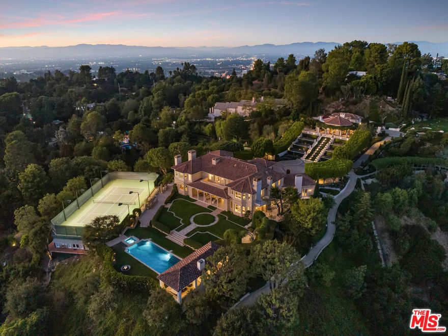 The Antelo View Estate stands as one of Los Angeles' most distinguished and irreplaceable residences, tucked away at the end of a secluded private road in Bel-Air. With nearly unmatched scale, privacy, and design pedigree, this exceptional compound encompasses two APNs and is secured behind double gates, unveiling a world entirely its own. A sweeping motor court welcomes guests with commanding views stretching from the glittering city skyline to the serene mountains and the Pacific Ocean beyond. Graceful fountains accent the arrival, their gentle flow enhancing the sense of tranquility and grandeur that defines the estate.  Completely reimagined through an extensive, design-driven remodel, the estate masterfully fuses timeless sophistication with modern innovation. The 6-bedroom, 9-bath main residence is defined by grand-scale interiors, filled with abundant natural light and breathtaking views from nearly every room. Stately fireplaces throughout the home offer warmth, dramatic presence, and intimate gathering spaces, anchoring living areas with a sense of refined elegance.  The lower level is a retreat for both leisure and entertainment, featuring a state-of-the-art theater with bar, a private gym with steam shower, wine storage, and flexible staff or wellness quarters. At the heart of the home lies a spectacular new chef's kitchen, curated with bespoke white oak cabinetry, hand-selected marble countertops, dual oversized sinks, and an array of Miele and Gaggenau appliances. An exquisite brass wine display, inviting fireplace, walk-in pantry, and breakfast nook with unobstructed views further elevate the space, transforming everyday living into an art form.  The second floor reveals four gracious bedrooms, crowned by a primary suite of rare distinction. The suite features dual spa-inspired baths, expansive walk-in dressing rooms, a fireplace for quiet evenings, a private office, and a vast terrace that embraces the horizon.  Beyond the main residence, two guest homes extend the estate's legacy of luxury. The upper two-story guest house presents nearly 3,000 square feet, complete with two bedrooms, three baths, a full kitchen, and a great room anchored by a dramatic fireplace. French doors open to garden terraces accompanied by gentle fountains and rolling lawns, crafting an atmosphere of serenity. The lower guest home, nestled under the tennis court, offers two bedrooms, two baths, a full kitchen, laundry, and wrap-around terraces immersed in tranquil treetop views perfect for long-stay guests or staff.  Outdoors, the grounds unfold in true resort style: a dramatic swimming pool with cabana, a tennis court with viewing pavilions, manicured gardens, and a romantic loggia designed for alfresco dining or intimate wine tastings. Fountain features dot the landscape, blending the soothing sound of flowing water with the natural beauty of the gardens. Interwoven pathways and a private golf cart circuit encircle the entire estate, underscoring its rare sense of scale and seclusion.  The Antelo View Estate is more than a home it is a private sanctuary of architectural beauty and natural majesty. With its many fireplaces, enchanting fountains, unrivaled vistas, world-class amenities, and a level of craftsmanship seldom seen, this legacy compound represents one of the most important and prestigious offerings to ever arrive on the market in Bel-Air.