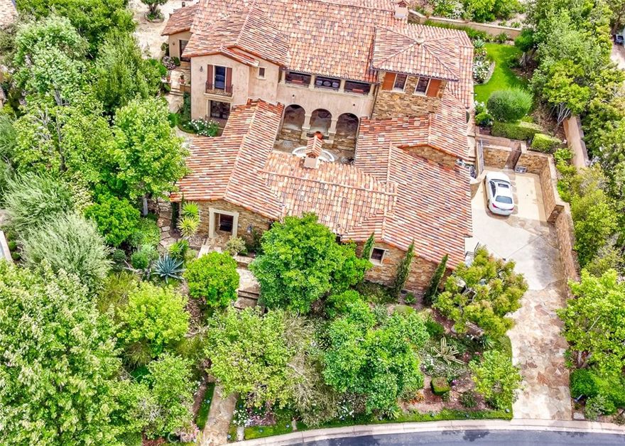 This stunning Tuscan-style custom home is a true gem, perfectly situated within the exclusive Shady Canyon golf community. Upon entering, you'll be greeted by a bright and airy atmosphere that flows seamlessly throughout the open-concept living spaces. The home's unique design revolves around a central courtyard, maximizing natural light and enhancing the indoor/outdoor living experience.
Inside, meticulous attention to detail is evident in the exquisite finishes, including luxurious marble countertops, hand-carved limestone fireplaces, and an extensive array of stone materials. Elegant lighting and exposed wood beams contribute to the home’s sophisticated ambiance, while custom ceiling treatments in the kitchen add a unique touch of character. The well-appointed kitchen, complete with high-end appliances and finishes, opens up to a welcoming family room highlighted by a cozy fireplace, creating an inviting atmosphere for gatherings.
Stepping outside, the backyard is a true retreat, featuring a sparkling pool, soothing spa, charming fountain, and a stunning waterfall, all surrounded by a variety of meticulously manicured trees. This exceptional home is not just a residence but a lifestyle, offering a perfect blend of luxury, comfort, and outdoor enjoyment in a prestigious community. With its unmatched features and prime location, it truly represents the pinnacle of Southern California living.