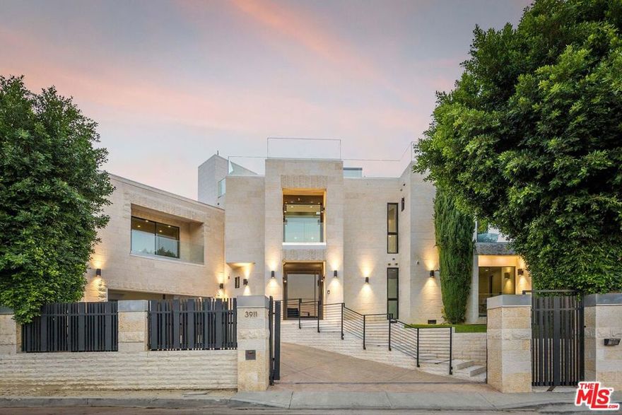 Tucked behind gates in prime Sherman Oaks, this newer 5BD/7BA estate blends privacy, sweeping views, and seamless indoor-outdoor living. A custom Kolbe glass entry sets the tone, leading into a dramatic main level with soaring ceilings allowing natural light to fill the space. A bar area and formal dining room allow plenty of space for friends and family to gather. The chef's kitchen features a 6-burner Wolf range, Miele appliances, a glass-front Sub-Zero, and a striking Cristallo White Quartzite island. Floor-to-ceiling pocket doors open to the resort-style backyard, designed with a covered patio, pool, spa, wood decking, and a full outdoor kitchen. An elevator takes you to the rooftop deck, where city, valley, and mountain views create the ultimate backdrop for entertaining. Two fire pits, a second outdoor kitchen, and a private shower round out this impressive space. Upstairs, dual primary suites showcase distinct luxuries. One offers a wraparound balcony with 180-degree views, swing seating, fire feature, and a spa-like bath with steam shower, rainfall heads, and a freestanding tub positioned toward the horizon. The other includes a fireplace, dual balconies, and a custom walk-in closet. Two additional ensuite bedrooms round out the level, one with its own kitchenette, private entry, and fireplace. Every detail has been thoughtfully selected, from electronic bidet toilets in each bathroom to the home theater, Blue Roma Quartzite fireplace, Yellow Onyx bar, and Jerusalem stone exterior. Just minutes from Ventura Boulevard and scenic hiking trails, this residence balances sophistication, comfort, and unmatched views. Also available for lease, inquire within.