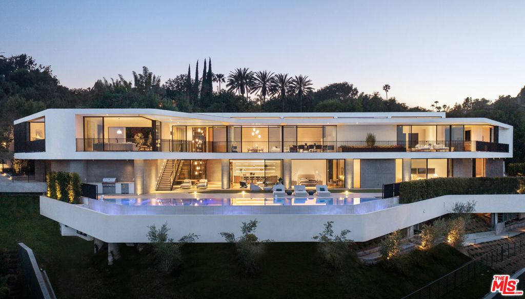 A newly completed, architecturally paramount masterpiece overlooking Bel Air Country Club's fairways, this nearly 17,000-square-foot Zoltan Pali vision has been brought to life as a standalone opportunity for unparalleled 2022 quality and superb design, whilst offering the classic pedigree and views of prime Bel Air. The home's horizontal yet fluid rhythm begins as the cobblestone courtyard unveils the skyline view, carries through the privately gated and modest entryway, and flows into an unassuming reveal of the 16,849-square-foot masterfully crafted seven-bed, eleven-bath residence with all three levels anchored by a striking staircase. The modernist architectural exterior was crafted with Indiana limestone and curved bronze metalwork to complement the tranquil refined palette, thoughtfully angled with a blended wall-cladding of travertine and board-form concrete and French walnut floors. A generous use of glass, sliding doors on each bedroom, and two levels of day-lit space with oversized spacious decks and an infinity pool together create an extension of outdoor living to the floor space. Overlooking a serene Japanese garden, the west wing of the top level offers an open kitchen with breakfast area complete with a blend of Miele, Wolf, and Sub-Zero appliances, Ceppo di Gre stone, dining room, expansive living room separated by travertine fireplace, and guest quarters. The southeast corner is devoted to the primary suite and the emerging olive treetop of the two-story courtyard. The lower level, an amenity showpiece, includes a junior primary suite, a gym, wellness center, family room, and additional en-suite bedrooms, all opening to the floating deck with pool and spa. The lowest level completes the home with staff quarters, a theater, and a wine room. A masterwork home by Viewpoint Collection, positioned on one of East Gate Bel Air's finest streets.