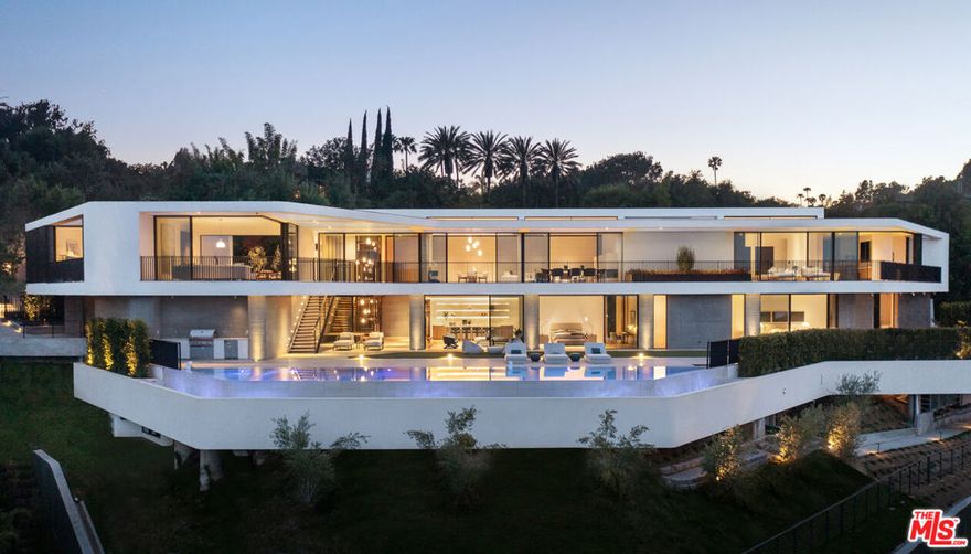 A newly completed, architecturally paramount masterpiece overlooking Bel Air Country Club's fairways, this nearly 17,000-square-foot Zoltan Pali vision has been brought to life as a standalone opportunity for unparalleled 2022 quality and superb design, whilst offering the classic pedigree and views of prime Bel Air. The home's horizontal yet fluid rhythm begins as the cobblestone courtyard unveils the skyline view, carries through the privately gated and modest entryway, and flows into an unassuming reveal of the 16,849-square-foot masterfully crafted seven-bed, eleven-bath residence with all three levels anchored by a striking staircase. The modernist architectural exterior was crafted with Indiana limestone and curved bronze metalwork to complement the tranquil refined palette, thoughtfully angled with a blended wall-cladding of travertine and board-form concrete and French walnut floors. A generous use of glass, sliding doors on each bedroom, and two levels of day-lit space with oversized spacious decks and an infinity pool together create an extension of outdoor living to the floor space. Overlooking a serene Japanese garden, the west wing of the top level offers an open kitchen with breakfast area complete with a blend of Miele, Wolf, and Sub-Zero appliances, Ceppo di Gre stone, dining room, expansive living room separated by travertine fireplace, and guest quarters. The southeast corner is devoted to the primary suite and the emerging olive treetop of the two-story courtyard. The lower level, an amenity showpiece, includes a junior primary suite, a gym, wellness center, family room, and additional en-suite bedrooms, all opening to the floating deck with pool and spa. The lowest level completes the home with staff quarters, a theater, and a wine room. A masterwork home by Viewpoint Collection, positioned on one of East Gate Bel Air's finest streets.