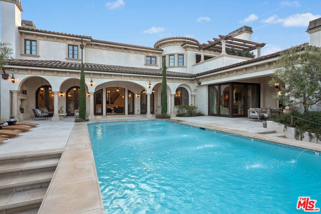Nestled on a coveted 16,008 sq. ft. lot in one of North Kentwood's most desirable neighborhoods, this extraordinary Mediterranean estate blends timeless elegance with modern luxury. Offering 8,733 sq. ft. of meticulously crafted living space and a 1,166 sq. ft casita, this private retreat showcases unparalleled craftsmanship and high-end finishes, including Italian marble, limestone, and natural woods, in a thoughtfully designed layout that exudes sophistication and warmth. The main residence features five bedrooms, seven bathrooms, and two half baths, complemented by a two-bedroom, one-bath guest house an ideal haven for multi-generational living or stylish guest accommodations. Both homes are fully equipped smart homes, powered by advanced Crestron technology, allowing seamless control of lighting, climate, security, and entertainment systems. Constructed with flame-retardant lumber, a robust water-softening and filtration system, solar panels, and a hard-wired security system with geo-fencing, the estate offers state-of-the-art innovation with enduring quality. Enter through the grand foyer, where soaring ceilings and a sweeping curved double staircase immediately set a tone of opulence. The open yet well-defined floor plan flows effortlessly between formal and informal living spaces. A stately formal living room with a gas fireplace and mahogany doors opens to the lush backyard, while the sophisticated formal dining room offers a perfect setting for elegant gatherings. The family room, featuring a striking coffered ceiling, pocket doors, and an outdoor fireplace, invites relaxation and seamlessly merges indoor and outdoor living. The heart of the home is an expansive kitchen equipped with high-end appliances, a La Cornue stove, a spacious marble island, and a separate chef's kitchen for effortless entertaining. A full-service wet bar enhances the home's hosting capabilities. The main level also includes a private office with coffered ceilings and French doors opening to the front loggia and garden, a hand-carved limestone staircase spiraling around a three-story touret with niche lighting, an adjacent powder room, and an elevator for added convenience. Designed for both grand entertaining and serene retreats, the backyard is a true sanctuary, featuring a large salt-water pool and spa, two outdoor fireplaces, and a tranquil fountain surrounded by lush, mature landscaping that offers exceptional privacy. Upstairs, the primary suite is a luxurious escape, complete with a private balcony offering sweeping views, a cozy fireplace, a spa-inspired ensuite bath with heated floors, a soaking tub, a separate shower, dual vanities, and a refrigerated bar area. Expansive dual closets provide impeccable storage. Four additional en-suite bedrooms ensure comfort and privacy for family and guests, while a conveniently located laundry room adds everyday ease. A first-floor en-suite bedroom, with a refrigerated minibar and French doors to the garden, offers flexibility and accessibility. Entertainment and lifestyle amenities abound, including a temperature-controlled wine cellar for collectors, a private state-of-the-art movie theater with custom seating, an adjacent full-service wet bar and snack center with microwave and refrigerated drawers, a full salon with hair and nail stations, a dedicated gift wrapping, hobby, and homework center, plus a large gym for wellness enthusiasts. The separate guest house offers fully independent living with a custom kitchen, washer/dryer, two large bedrooms, a full bath, and a separate outdoor pool bath, ensuring extended family or guests enjoy complete comfort and privacy. A four-car garage and a gated driveway provide secure parking for six or more vehicles, adding everyday practicality to the estate's grand presence. This rare offering presents a unique opportunity to own an estate that flawlessly blends luxury, functionality, and exquisite design all within the vibrant heart of Westchester.