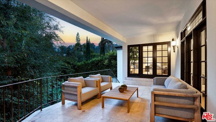 Tucked into one of Angelo Drive's most coveted enclaves, this masterfully renovated mid-century residence blends classic 1960s architecture with elevated contemporary upgrades, thoughtfully integrated to preserve the home's mid-century character. Set on a secluded drive just moments above Sunset Blvd, the property offers unmatched privacy and tranquil treetop outlooks.Beautifully reimagined, the approx. 3,400 SF floor plan includes 4 bedrooms and 4 refined baths, with expansive, sun-filled living spaces framed by restored French doors and oversized windows. A deep wraparound balcony connects the living room, dining room, and primary suite, creating a seamless indoor-outdoor flow. The sun-washed chef's kitchen features a generous stone-topped island, premium stainless appliances, custom cabinetry, and a sunlit breakfast nook. The primary suite opens directly onto the terrace and enjoys serene garden views and a spa-inspired bath with dramatic stone finishes, large walk-in shower, and a deep step-down soaking tub. Curated upgrades throughout include new flooring, renovated bathrooms, designer lighting, refreshed finishes, and improved systems. The grounds include mature landscaping, a spacious terrace for dining and lounging, and a wide motor court with covered parking. A refined, mid-century retreat in one of BHPO's most discreet pockets-offering privacy, architectural charm, and effortless access to Beverly Hills, Holmby Hills, and top-rated Warner Avenue Elementary.