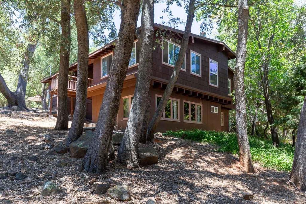 Cozy hidden mountain retreat nestled among groves of oaks, cedars and pines. This custom home offers a quiet space to enjoy each day. Snuggle up to the warm wood stove during the lovely winter months. A bright and open living room space boasts of a wood beam ceiling. The spacious primary bedroom includes a nice sitting area with delightful views. The enclosed deck area affords more space to use for perhaps a home office or gym. A whole house generator provides a bonus during occasional power outages. Watch the shuffle of deer and turkey slip through the woods while listening to a chorus of birds singing. The serene and peaceful setting makes this property unique. This usable 1.74 acre lot is located in the desirable Julian neighborhood of Pine Hills. Two conveniently placed sturdy sheds deliver ample storage space. Seasonal lilacs, blackberries, daffodils and floral vinca enhance the natural landscape. Here, amid nature’s beauty and the comfort of a well-loved home, find the sanctuary you have been seeking. County and state parks nearby offer fishing and miles of hiking. The historic town of Julian is approximately five miles away boasting of restaurants and local shopping as well as delicious apple pies.