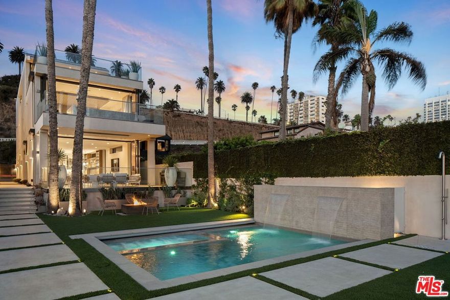 A rare beachfront trophy estate, this modern new-construction masterpiece defines contemporary coastal living at its finest. Spanning four levels with 4 bedrooms and 5.5 baths, the residence blends scale, sophistication, and effortless functionality for both refined entertaining and everyday living. Floor-to-ceiling glass frames sweeping Pacific Ocean vistas, allowing the landscape to flow seamlessly into the interior. The main level designed for effortless indoor-outdoor living makes a dramatic impression with a spacious living and great room, all opening directly to an expansive oceanfront deck. A showpiece chef's kitchen featuring a sculptural island and custom built-in banquet seating flows seamlessly into the entertaining areas, designed to capture panoramic ocean views and natural light. Outdoors, the private retreat includes a pool and spa with cascading waterfalls, firepit, multiple lounge areas, and a fully equipped outdoor kitchen. The second-floor primary suite is a sanctuary of light, privacy, and luxury, opening to its own terrace with a private pool overlooking the Pacific. The suite also includes an impressive spa-inspired bath and dual dressing rooms, while an additional en-suite bedroom and lounge area complete the floor. Two more en-suite bedrooms occupy the third level, and the lower level offers a state-of-the-art theater. Meticulously curated with exquisite architectural details, striking staircases, high-end finishes, state-of-the-art smart-home technology, solar panels on the roof, an elevator, a showcase wine cellar, and a two-car garage with an innovative mechanical car turntable, this residence is unmatched in its design and execution. Offered individually or together with its sister property at 938 Palisades Beach Rd for $38,500,000, this estate represents a rare opportunity to own an extraordinary beachfront residence along Santa Monica's coveted Gold Coast.