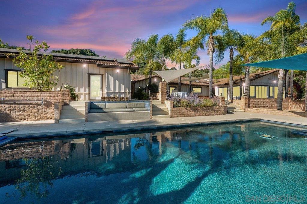 Discover this exceptional ranch-style estate located in the Gird Valley with panoramic views of Monserate Winery Vineyard, thoughtfully designed for luxury, comfort, and functionality. Located in a friendly, established neighborhood with no HOA or Mello-Roos, this expansive home offers privacy, modern amenities, and room to breathe. Light and bright throughout, the home is filled with natural light from multiple skylights, creating an inviting atmosphere in every space. Inside, enjoy Dual Primary Suites, each with walk-in closets and spa-like ensuites—one featuring a corner jacuzzi tub, huge walk-in shower, and an oversized closet. The heart of the home is a massive Great Room with a gas-starter fireplace, 5.1 surround sound, and custom media cabinets, flowing seamlessly into a chef’s dream kitchen. Outfitted with Absolute Black leathered granite, walnut cabinetry, and a Technogas Superiore 48” Italian commercial range with dual ovens, gas burners, induction cooktop, and electric griddle. Dual refrigerators, a Bosch dishwasher, and an oversized walk-in pantry complete the kitchen. Enjoy upgraded finishes throughout, including Italian porcelain tile, polished concrete flooring, and new HVAC and ducts (2018). Stay cool with 9 zoned mini-splits (2022) and 7 ceiling fans. A central vacuum system adds everyday convenience. Energy efficiency shines with owned solar, 400 amp service, and 4 subpanels. A permitted 384 sq ft shed with electricity and its own mini-split provides flexible space for a workshop, studio, or guest retreat. See supplement. Smart home features include programmable sprinkler systems tied to a personal weather station, managing water usage across an expansive 63 tree fruit orchard, including avocados, citrus, stone fruits, olives and even a macadamia nut tree. Outdoors, relax in your 35,000-gallon salt water pool (fully redone in 2018) with dark pebble tec finish, new tile, and automated app-controlled spa, lighting, and filtration. Roof was re-papered in 2024 with 40-year underlayment and ample spare tiles included. Other highlights: 3-car garage with 208V power for a workshop and full ¾ bathroom Two wood-burning fireplaces with gas starters Gated RV parking + space for 10+ cars City connected water, sewer and natural gas. Toto electric bidets and abundant walk-in storage, including a pantry, linen closet, storage room, and office area. This rare home blends high-end upgrades with serene vineyard views in a welcoming community—offering the ultimate Southern California lifestyle.