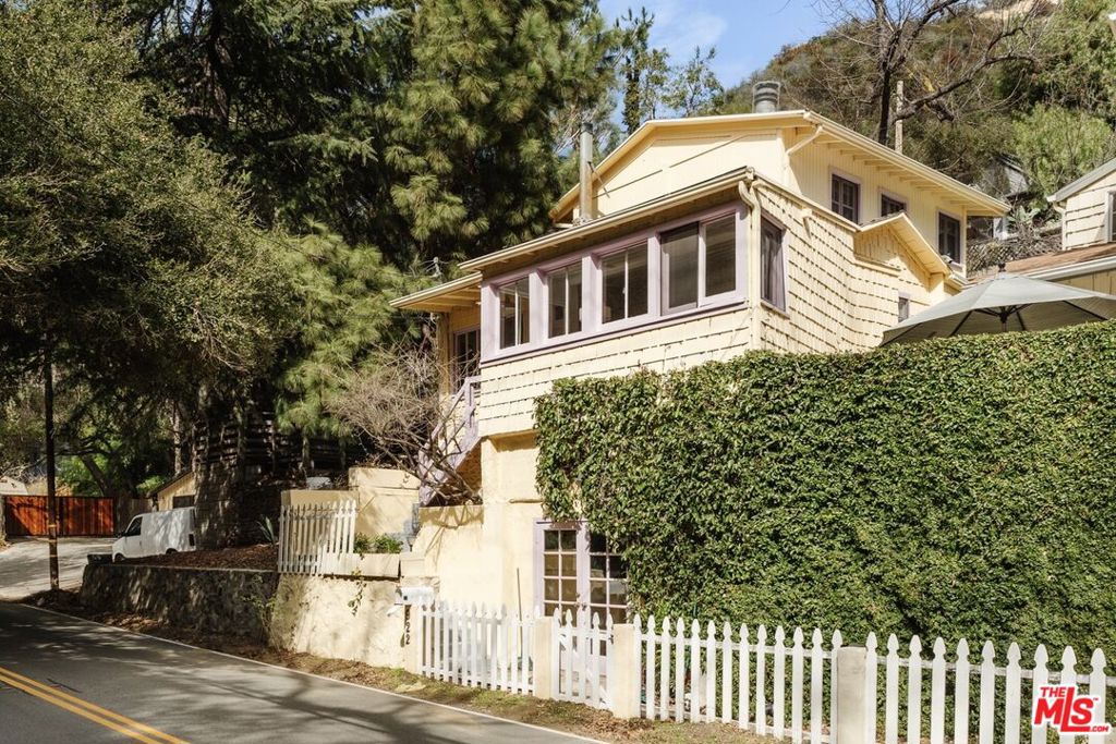 One of Topanga's original 1920s cabins, beautifully restored to preserve the charm of a bygone erawhen the creek teemed with fish and locals rode horses bareback down Old Topanga Canyon. Step into a sun-filled living room with views of Strawberry Peak, featuring a gorgeous river rock fireplace and a handsome kitchen bar, inviting you to pull up a stool, enjoy a beverage, or keep the cook company. A quaint patio, just outside the kitchen's Dutch door, offers mountain views and a sunny spot for your morning coffee.Upstairs, a generous primary suite awaits, boasting vaulted beamed ceilings, an updated bath, and its own fireplace. An additional bonus space, previously used as an art studio, adds live/work flexibility. Ideally located just minutes from Topanga Town Center and a short distance from hiking trails in Red Rock, this beautiful retreat is ready to become your Topanga sanctuary.