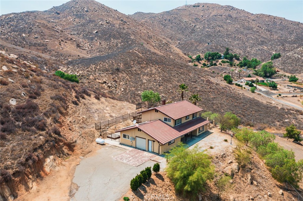 Sitting alone atop a mountain at the end of an extended private driveway, this 4-bedroom retreat delivers unmatched privacy, sweeping mountain views behind, and dazzling 270° city lights in front. Backed by Box Springs Mountain Reserve, the nearly 2-acre property offers complete self-sufficiency with a private well and paid-off solar panels—and no utility bills make off-grid living possible—without sacrificing modern comforts.
Inside, warm wood finishes, a stone fireplace, chef’s kitchen, and spacious bedrooms create a cozy, timeless feel.
while spacious bedrooms and a separate office add flexibility. The primary suite boasts an oversized terrace perfect for soaking in the stunning vistas.
Enjoy space for an ADU, stables, or RV/boat parking.
Just 10 minutes from grocery stores, Moreno Valley Mall and all the shopping & dining along the 60 Fwy. Plus, you can jump on I-215 in no time at all, with UC Riverside & downtown Riverside less than 20 minutes from your front door!, this rare mountaintop haven blends off-grid freedom with city convenience—don’t miss it!