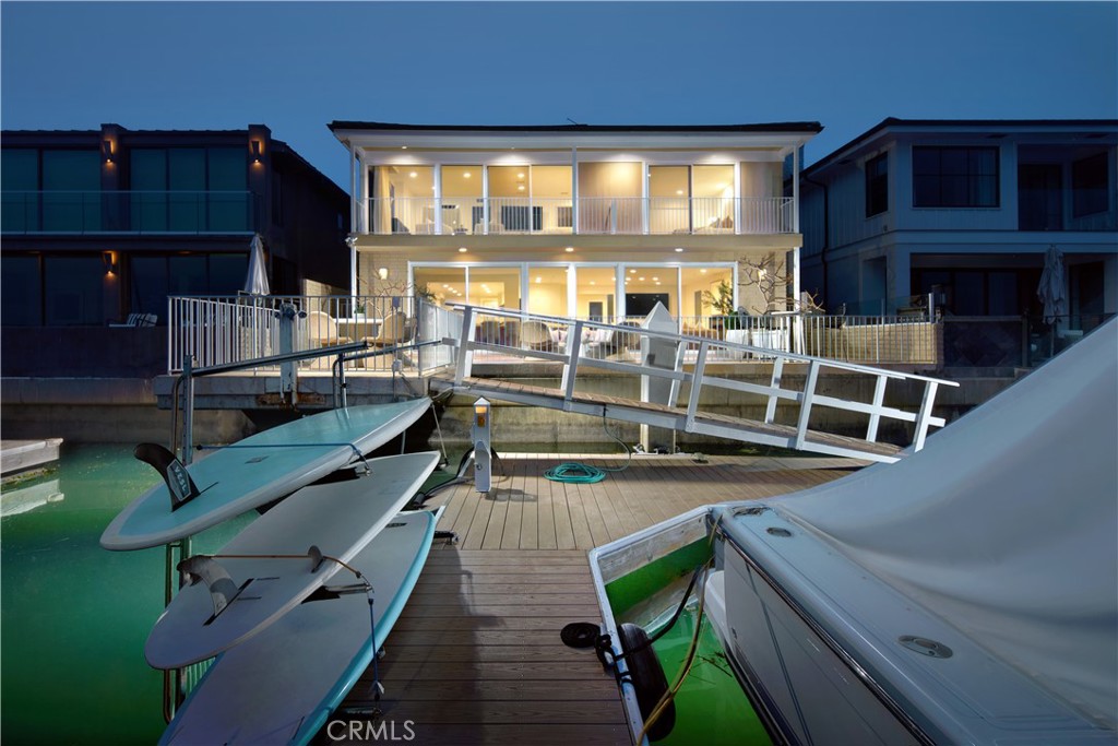 The ultimate expression of Newport Beach’s enviable waterfront lifestyle awaits at this classic Mid-Century Modern custom home on guard-gated Linda Isle. With a location on the exclusive island’s preferred western edge, the residence offers magnificent views of Newport Harbor, evening lights, sunsets, and sailboats and yachts that gently glide by. A bayfront terrace includes a private dock for a vessel up to appx. 57’ and provides an outstanding location for impressive entertaining along the water’s edge. Boasting eight spacious bedrooms and seven-and-one-half baths, the generously proportioned home offers an equally welcoming introduction thanks to custom artist-crafted metal and glass gates that open to a large entry courtyard. Grand modern style continues indoors, where a two-story foyer is anchored by a stunning spiral staircase that appears to float on its own while illuminated by floor-to-ceiling windows. Harbor views are enjoyed upon entry to the open and bright residence, which spans approximately 4,598 square feet. Water-view entertaining is destined to be enjoyed in a fireplace-warmed living room and dining room area that opens to the bayside terrace and hosts a step-down walk-in wet bar with wine refrigerator and new quartz countertops. Brand-new quartz also graces the counters and backsplash in a large kitchen that displays frameless white cabinetry, a nook, peninsula bar, two four-burner cooktops, and a built-in Sub-Zero refrigerator. Two en suite bedrooms are located on this level and include one that is perfect as a home office. A large landing at the top of the staircase leads to six more bedrooms, including two that share a bath, an en suite with balcony overlooking the courtyard, and an en suite with spacious bath and harbor-view balcony. The primary suite is enormous and features double entry doors, an intimate lounge, private bath, fireplace-warmed sitting area, and priceless bay views from indoors and a wide balcony above the rear terrace.