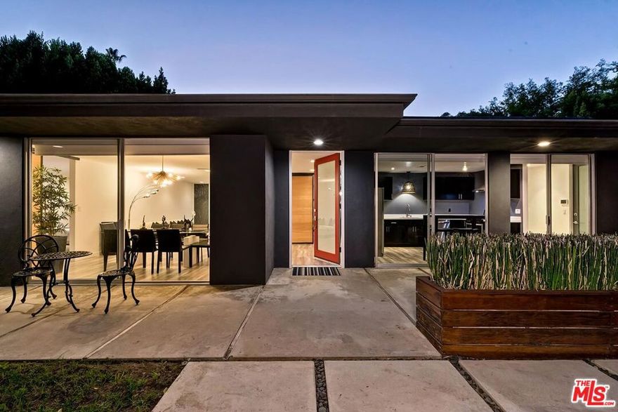 A signature example of mid-century modern design reimagined for today's resort-style living. Beyond a quiet, set aback, understated black architectural facade and tree lined private gated drive, this residence exudes sophistication and discretion from the moment of arrival. Positioned on an expansive, lushly landscaped lot, the property unfolds into an idyllic retreat centered around outdoor courtyards and walking pavers all leading to an in-ground pool with integrated spa. Framed by manicured lawns, mature Ficus hedges, and curated landscape lighting, the grounds evoke an atmosphere of serenity and seclusion. The seamless flow between indoor and outdoor living is accentuated by walls of glass doors that bathe the interiors in natural light and reveal verdant views from every angle. Inside, the home's mid-century spirit is expressed through clean lines, open volumes, and natural textures. The living, dining, and kitchen areas connect effortlessly, offering perfect fireside setting for both intimate gatherings and formal sophisticated to casual entertaining whims. Sliding glass doors open directly to the pool terrace and lawn, creating a true resort-style ambiance found hiding amidst Los Angeles and Hollywood life. The primary suite serves as a private sanctuary with serene pool and garden views, a spacious walk-in shower, and a spa-inspired bath. Additional guest suites mirror the home's elegant design, providing comfort and privacy for family and guests alike. Perfectly situated near the fine dining, coffee cafes, and boutique shops of Tujunga Village, Studio City, and Toluca Lake Village, this residence also offers unmatched convenience to the NoHo Arts District and major studios including Warner Bros., Disney, and Universal. With its modern architecture, private resort setting, and premier Toluca Lake location, 11230 Dilling Avenue embodies the essence of contemporary California living - elegant, effortless, and exquisitely private.