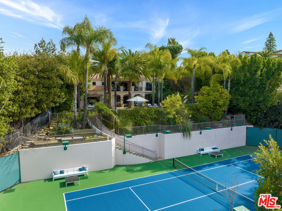 You will be safely ensconced behind the 24/7 security gates of the coveted Mulholland Estates long before you set foot in this magnificent Mediterranean-styled villa. A few short steps down the entryway past the grand double doors is your entry into the spacious ground floor living areas. The large foyer, complete with high ceiling and warm stone floor, welcomes you and your guests in regal fashion and leads directly to the formal living room with its fireplace and well-proportioned glass doors with access to the covered deck and private yard. The generously-sized kitchen features a stone island, professional-grade appliances, including a Wolf range and grill, and space for breakfast seating indoors and out, is flanked by the 12-seat formal dining room, butler's pantry, and built-in wet bar for your convenience when entertaining or on those quiet nights alone. The main floor includes a comfortable family room with fireplace, and office, powder room, and maid's quarters with en-suite bathroom. The lush and tranquil backyard is highlighted by the pool with hot tub, water slide, waterfall, and a recently resurfaced personal tennis court. When retiring for the evening, you will appreciate the upper floor sumptuous primary suite with grand fireplace and French doors that lead to a private balcony. Dual en-suite baths are appointed with soaking tub, steam shower, and individual walk-in closets. Three additional guest rooms with en-suite baths await your family and friends. A library completes your upper floor sanctuary. This 6.935 sqft estate offers you access to amenities like tennis, pickle, basketball, squash, and racquetball courts, a playground and community center in esteemed Mulholland Estates.