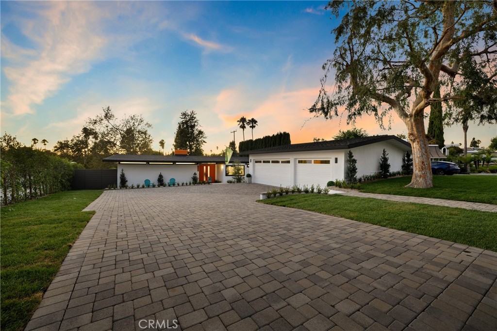 Welcome to 5491 Rockledge Drive, an exquisitely redesigned Eichler-style home in the coveted Bellehurst View Estates of Buena Park. This light-filled 4-bedroom, 2-bathroom home sits on an oversized 12,600 sqft lot, offering breathtaking vistas of the Los Coyotes Golf Course. Step inside to a spacious living area with a custom fireplace, floor-to-ceiling windows that fill the space with natural light, and an open-concept layout that seamlessly connects indoor and outdoor living. At the heart of the home lies a gourmet chef’s kitchen—a perfect blend of mid-century simplicity and modern functionality. It features decorative ceiling beams, abundant natural light, generous counter space, top-of-the-line stainless steel appliances, and an oversized island with bar-top seating, ideal for cooking and entertaining. Adjacent, the dining area boasts an elegant linear pendant and a custom wet bar with natural-tone tile and decorative shelving. All bedrooms are spacious and bright, with the primary suite offering additional closet space, a private side deck, and an en-suite bathroom. Both bathrooms are beautifully designed with natural-tone finishes and a sleek, modern aesthetic. Additional updates include newer central AC, roof, LVP flooring, surround sound, and recessed lighting. Enjoy breathtaking backyard views Overlooking rolling fairways and lush greens, the outdoor space offers a serene, resort-like setting perfect for entertaining or relaxing in privacy. Whether hosting gatherings on the patio or simply taking in the tranquil scenery, this home provides a unique blend of elegance, open space, and connection to one of Buena Park’s most prestigious golf courses. The home also features a 6-car garage, ideal for car enthusiasts or extra storage. Located in a quiet, tree-lined neighborhood, this home provides easy access to shopping, dining, parks, and top-rated schools. Experience the perfect balance of mid-century charm, modern comfort, and prime location. Schedule your showing today!
