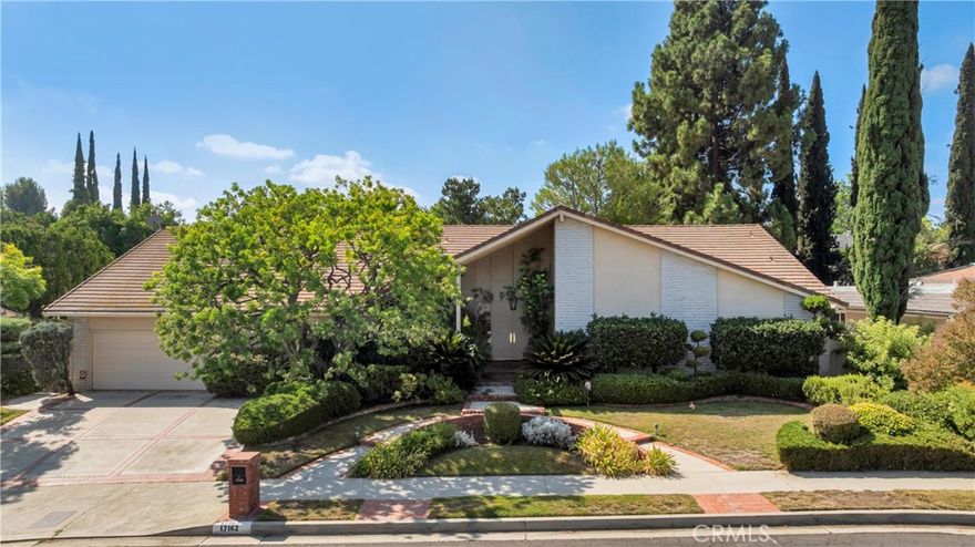 Wonderful, mid-century, ranch-style, 5 bed, 3.5 bath, over 3700 sqft home set on an expansive 16,228 sqft lot in quiet residential neighborhood in Northridge blends timeless architecture with spacious comfort. Great curb appeal with A-frame roofline, white brick panels, wide drive with brick ribbons, circular walkway, and manicured green lawn framed by hedges and shade tree. Elegant double doors open into a formal entry and open, inviting home, with tasteful and elegant touches like parquet floors, crown molding, high ceilings, and recessed lighting throughout. Formal sunken living room is a bright and airy space, perfect for entertaining and gatherings with French doors to the patio, and open flow to the dining area and sunken conversation pit. Dining room showcases a wide archway, lighted cabinetry, and passthrough to the conversation pit, which features a marble-surround fireplace, wet bar, and built-in shelves for display. Expansive, informal family room offers built-in shelving, French doors to the yard, and a pass-through to the bright eat-in kitchen. Kitchen boasts white cabinetry, white appliances, granite counters and backsplash, and a cozy breakfast nook. A powder bath and dedicated laundry room add convenience, while a nearby private bedroom with adjacent ¾ bath is perfect for guests or a home office. Down the hall, the primary suite impresses with double-door entry, mirrored walk-in closet with custom built-ins, generous space with room for a sitting area and French doors to the backyard. The en-suite, spa-style bath offers heated tile floors, marble counters, beveled mirrors, plantation shutters, jetted soaking tub, and separate shower. Three additional, sizable bedrooms with large windows, including one arranged as a study with built-in bookshelves and desk that could be converted back, share a full hall bath with dual-sink marble vanity and access to the side yard. Additional features include dual pane windows, dual zone HVAC, dual water heaters, and an attached 2-car garage with overhead storage and direct access. The spacious backyard is a true retreat with a large pergola-covered deck, in-ground pool with brick coping, sprawling lawn, and mature landscaping. Well situated in Granada Hills Charter district, near shopping, dining, recreation, and entertainment, CSUN, local parks, and major transportation arteries. This property offers both immediate comfort and a canvas for personalization in prime Northridge setting. Don’t miss out!