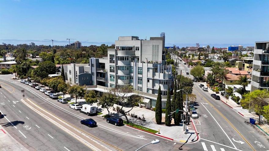 Rare corner residence at DECA offering over 500 sqft of private outdoor space—an entertainer’s dream that truly lives like a million-dollar home. Dramatic curved window walls, soaring concrete ceilings, and refined upgrades set this modern Hillcrest condo apart from anything else in its price range. The expansive wraparound terrace and open corner layout create an incredible through-breeze, inviting San Diego’s signature coastal air indoors and making every day feel like a retreat. Inside, a chef’s kitchen equipped with Sub-Zero, Wolf, and Miele appliances flows seamlessly into an open living area bathed in natural light. Custom finishes, sleek architectural lines, and a spa-inspired primary suite create a level of sophistication rarely seen at this price point. DECA’s boutique 37-unit community offers secure entry, fitness center, rooftop decks with panoramic views, and garage parking with EV charger. Perfectly positioned in the heart of Hillcrest—just steps to Balboa Park, the weekly farmers’ market, and Uptown’s vibrant dining and nightlife—this one-of-a-kind residence delivers the indoor-outdoor lifestyle most only dream of. Experience design, privacy, and outdoor living that rival homes twice the price.  Only one of its kind in the building — no other DECA residence offers a wrap around patio outdoor space or corner light exposure. Thoughtfully upgraded throughout with designer lighting, premium flooring, custom window treatments, and organized closet systems. The terrace extends the living area year-round, creating a true indoor-outdoor lifestyle rarely found in Hillcrest. Solid concrete construction provides exceptional sound insulation and privacy. Garage space is has dedicated EV charging. Easy access to Downtown, airport, and freeways, while still walkable to Balboa Park, Hillcrest’s farmers’ market, and neighborhood cafes. Truly turn-key and unmatched in its price range — comparable homes would easily exceed $1M.