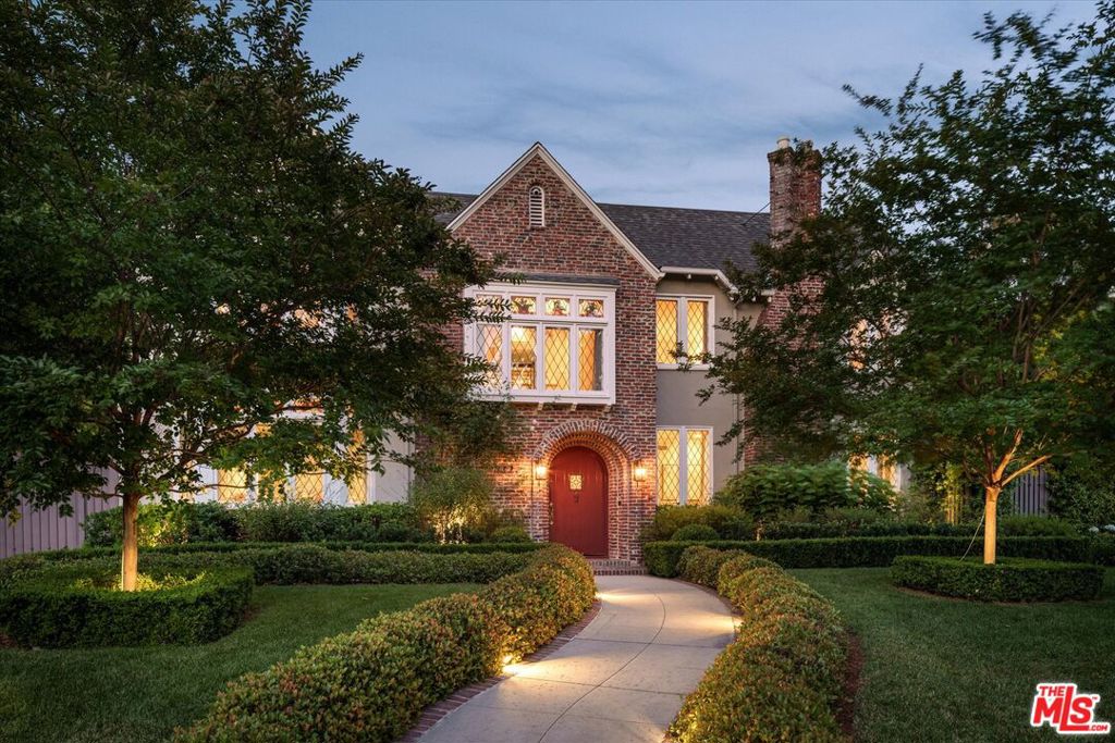 Set in the prestigious Windsor Square enclave of Hancock Park, this stately English Tudor designed by Robert D. Jones in 1926 epitomizes timeless grandeur and refined elegance, moments from the best that Larchmont Village offers. Upon entry, stained glass windows and hardwood floors warmly welcome guests, setting a tone of approachable sophistication that continues throughout the home. The formal living room showcases intricate crown moldings, rich wood-paneled walls, and a meticulously restored fireplace and hearth. Adjacent is an expansive yet inviting sitting room, complete with extensive library shelving, a second cozy fireplace, and direct outdoor access, perfect as an expanded informal living room or additional play room. The newly designer renovated chef's kitchen is a culinary masterpiece featuring a spacious island, luxurious marble surfaces, abundant storage, and premium Wolf and Sub-Zero appliances, complemented by a charming breakfast room. Strategically positioned between the kitchen and west-facing formal dining room, is a newly updated dry bar and pantry, featuring custom shelving and a wine fridge, enhancing entertainment possibilities.Upstairs, four generously sized bedrooms await, each featuring ensuite bathrooms and sizable closets. The luxurious west-facing primary suite boasts an expansive closet, fireplace, sitting area, and spacious ensuite bath. A complementary west-facing guest suite offers ample living space, closets, and picturesque tree-lined views. Two additional bedrooms share access to a delightful bonus roomideal as a play room or sun-filled home office. The cozy downstairs guest suite, featuring a private side entrance, provides convenient accommodations for a nanny, au pair, or extended family and friends. Custom window treatments and designer wallpaper throughout underscore meticulous attention to detail echoed throughout the residence. The professionally landscaped grounds form an idyllic setting for outdoor entertaining, relaxation, and play. A temperature-controlled covered patio, crafted from elegant Salado natural stone and equipped with built-in heaters, invites year-round dining and gatherings around a restored vintage fountain. Distinct landscaped zones, including floral gardens, a chef's herb garden, and a flat grassy lawn, enhance the property's expansive feel. The sparkling salt-water pool, secured by newly installed iron safety gates and an automatic cover, offers ample space for lounging and socializing. Additional outdoor amenities include a newly built outdoor kitchen with a gas grill, pizza oven, refrigerator, ice machine, and a newly installed play structure. The recently renovated bonus house provides versatile living with a kitchenette and 1.5 bathrooms, ideal for visitors, a separate detached home office, or gym. Additional conveniences include a fully renovated laundry room, fully wired multi-zone Denon sound system, new carpeting in the bonus house and primary closet, a two-car garage, and ample gated parking on the covered carport. 322 Lorraine represents an exceptional opportunity to acquire a meticulously restored Hancock Park legacy property, thoughtfully designed to combine luxurious living and seamless entertaining. This extraordinary residence effortlessly blends historic opulence with tasteful modern upgrades, creating an unparalleled living experience able to last for generations.