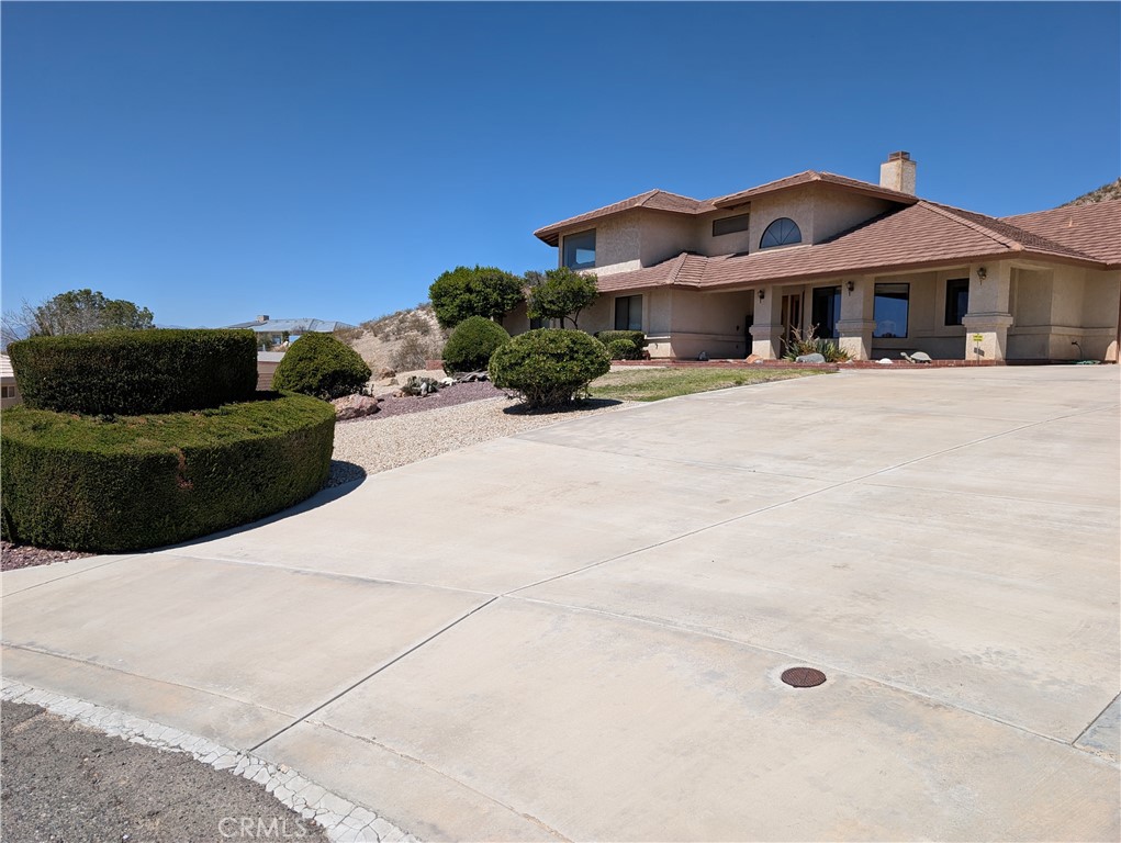 Welcome to this spacious and elegant custom home located in the prestigious Desert Knolls Manor area of Apple Valley. This 4-bedroom, 3.5-bathroom estate spans approximately 3,491 sq ft and sits on a beautifully landscaped ¾-acre lot. Designed for both comfort and functionality, the home features formal and informal living areas, a large breakfast dining space, a generous kitchen with ample counter space and cabinetry, and oversized bedrooms—each with walk-in closets. The central vacuum system, two A/C units, and well-maintained mechanicals ensure year-round comfort and energy efficiency.
The luxurious primary suite includes a spa-style bath complete with dual vanities, soaking tub, and skylights that bring in warm, natural light. Additional skylights brighten the covered back patio, creating an ideal setting for entertaining or relaxing in comfort. A spacious upstairs loft provides a Million Dollar View of the entire Apple Valley, and features a wet bar, built-in storage, and a private half bath—making it the perfect space for a game room, office, or guest retreat. There is a mini-split in the Office/Library/5th Bedroom behind the garage.
Step outside to a thoughtfully designed backyard with a dog run that includes running, and plenty of room for expansion. Whether you dream of adding a pool, spa, or garden, there’s ample space to bring your vision to life. A bonus detached garage in the back offers space for toys, a workshop, or a home gym, and the charming she-shed is ready for hobbies, crafts, or quiet escapes. The 3-car attached garage offers even more storage and convenience.
Desert Knolls Manor is one of Apple Valley’s most sought-after neighborhoods, known for its wide streets, executive-style custom homes, and its proximity to St. Mary’s Medical Center, local schools, golf, shopping, and dining. Homes in this community are in high demand due to lot size, pride of ownership, and accessibility.
With its blend of quality construction, smart layout, and prime location, 16560 Koda Rd is competitively positioned in today’s market. This is a rare opportunity to own a truly custom, view-filled home in one of the High Desert’s premier neighborhoods.