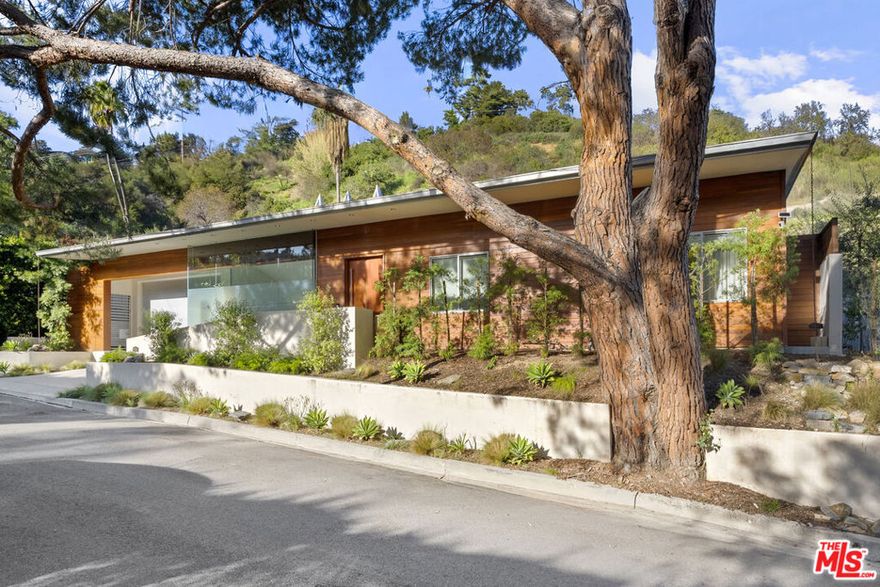 Welcome to this Mid-Century Modern private, gated and beautifully remodeled home. An oasis perfect for entertaining your most discern guests. Located in a nice, quiet and peaceful cul-de-sac tucked away in the serenity of nature. This home is light and bright with an open concept floor plan perfect for indoor and outdoor living with backside floor to ceiling sliding glass doors. You will love the gourmet Euro-style kitchen including Viking appliances, granite counters, and beautiful modern cabinetry. A choice to have a sunken dining room area or formal living room. Spacious primary suite with plenty of closet space, bathtub and separate shower. Two additional en-suite guest bedrooms, one of which is perfect for your home office. A vintage mid-century modern freestanding fireplace accentuates your family room venting through the ceiling in dramatic fashion. Your private backyard retreat with pool, spa, space for barbeque set up and multiple seating areas is perfect for outdoor parties. Beautiful hardwood and tiled floors, central air, and two-car garage with direct entry. This home offers elegance with comfort at every turn. Close proximity to groceries, restaurants, shops and entertainment on both sides of Mulholland Drive. A few minutes to Carpenter Charter Elementary School. Come live the dream.