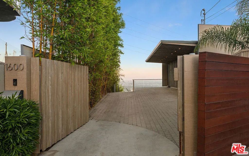 Architectural View Estate | Viewmont Heights Perched above the Sunset Strip in gated privacy, this striking modern residence offers panoramic jetliner views from downtown to the ocean. Spanning 4,400+ sq ft, the 4BD 4.5BA layout is defined by clean lines, open-concept living, and seamless indoor-outdoor flow through disappearing glass walls. The chef's kitchen features high-end appliances, custom cabinetry, and a large island ideal for entertaining. The primary suite includes a private view balcony, walk-in closet, and spa-like bath with soaking tub. Multiple limestone terraces (approx. 1,000 sf), a large hot tub, scenic overlook, and lush xeriscaped grounds elevate the outdoor experience. Gated motor court parking for 6. If purchasing, Includes two contiguous parcels totaling over 20,000sqft, offering potential to expand or double the buildable footprint.