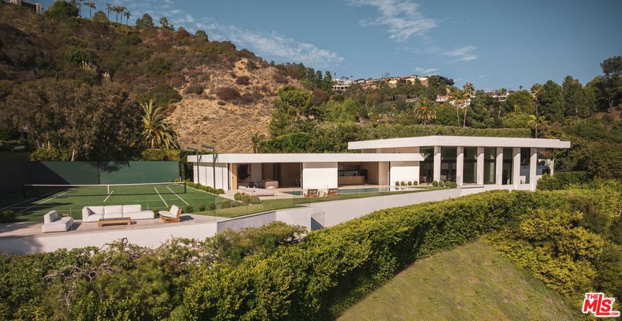 The Trousdale Oasis: Trousdale's most exquisite modern interpretation of the greatest era and lifestyle the world has ever known. One-of-a-kind tennis court estate on a double lot with explosive views. Designed by the legendary Edward Fickett, FAIA, king of the tennis court estates. The Mid-Century restoration of the ages, is a masterpiece born of the finest materials, leading style masters, and most coveted soil on earth. With the longest frontage of any house in Trousdale, it offers unobstructed panoramic views from the city to the ocean and as far as the eye can see. Set behind gates and lush 100-year old olive trees to provide the ultimate privacy and security. Open floor plan with 18-foot ceilings, exquisite finishes throughout including fluted Venetian plaster walls and rare blanco Travertine floors mixed with herringbone Fench Oak floors. Oversized family, dining, and living spaces with walls of glass to showcase the views. Arclinea kitchen features Miele appliances, and cabinets by Antonio Lupi. Custom bronze bar with wine cellar. The spacious primary suite has his and her separate bathrooms and walk-in closets, and balcony with views. Pocket glass doors disappear for seamless indoor/outdoor living. Lautner zero-edge swimming pool, spa, outdoor kitchen, fire pits, and multiple seating areas to take in immaculate views. The full-size North/South tennis court has grandfathered-in tennis court lights, which can never be done again in Trousdale. Now is your chance to own a piece of architectural history and luxury in the most exclusive neighborhood with the highest comps in the city, where every detail is designed for the ultimate in elegance and comfort, making this estate a truly once-in-a-lifetime opportunity to live the Beverly Hills dream.