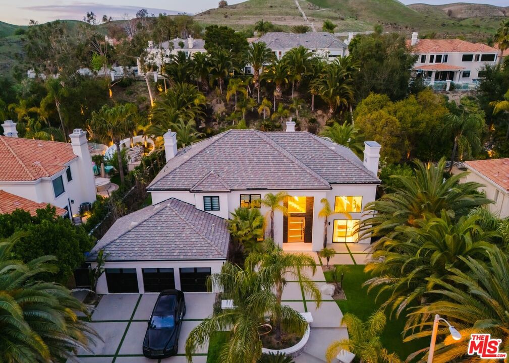 Nestled in a serene cul-de-sac within the prestigious guard-gated Mountain View Estates, this extraordinary contemporary smart home spans 4,800 square feet of meticulously designed living space. Recently renovated with no detail overlooked and no expense spared, it offers an entertainer's dream environment where style and functionality merge seamlessly. Designed for an exceptional indoor/outdoor lifestyle, 18-foot Fleetwood pocket doors open to an expansive outdoor retreat, complete with a zero-edge pool, spa, and three cascading waterfalls. The private oasis features beautiful wood decks, majestic king palms, a double-island outdoor kitchen, fire pit, and an immersive, amphitheater-quality sound system. The grand primary suite occupies the entire rear section of the home and serves as a luxurious sanctuary. With a floating steel staircase, Italian porcelain floors, reclaimed wood accent walls, and custom 3-gang LED fixtures, this space exudes sophistication and tranquility. The suite also includes a cozy lounge area, a fireplace, spacious walk-in closets, and opulent rose gold hardware and fixtures. For the culinary enthusiast, the chef's kitchen is a masterpiece, boasting high-end Miele appliances, custom glass cabinetry, and a striking butcher block center island. This residence exemplifies modern luxury, offering an unmatched combination of contemporary style, cutting-edge technology, and extraordinary outdoor living spaces.