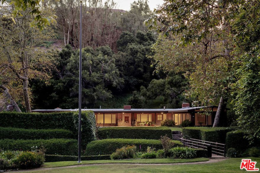 A once-in-a-generation opportunity in Rustic Canyon, this single-story mid-century modern home offers a rare combination of privacy, space, and natural beauty. Set on an expansive 56,000 square foot lot, the property is enveloped by mature landscaping, a gently flowing creek, and the quiet calm of canyon living. The 4-bedroom, 4-bathroom residence spans nearly 3,000 square feet and is thoughtfully designed to embrace its surroundings. Floor-to-ceiling windows in the living room frame tranquil views and bathe the interiors in natural light. Clean architectural lines and organic materials create a timeless atmosphere that blends seamlessly with the outdoors. The oversized lot provides a range of outdoor experiences. A large upper yard features a sparkling pool, while a footbridge crosses the creek and connects to a spacious flat lawn, perfect for entertaining or future enhancements. With its scale, setting, and versatility, this property presents a unique opportunity to expand, customize, or simply enjoy as a peaceful retreat. Positioned on a private road and just minutes from the park, this is one of most picturesque properties on the westside.