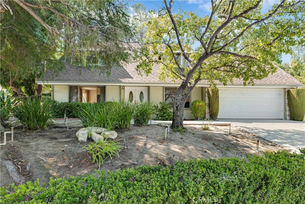 This great home is ideally situated at the end of a quiet cul-de-sac in one of West Hills’ most sought-after neighborhoods. Set on a huge 12,182 sq. ft. lot, its manicured hedges, mature shade trees, colorful flowerbeds and welcoming covered brick entryway create standout curb appeal. Double doors with frosted glass inserts open to a bright and flowing, open concept floor plan, offering approximately 2,182 sq. ft. of living space. The generously sized, sun-drenched living room features a raised-hearth brick fireplace and wall-to-wall carpet. The cook in the family will truly appreciate the thoughtfully designed and updated kitchen with its tray ceiling, recessed lighting, ceiling-height wood-grained cabinetry, Corian® countertops, full tile backsplash, dual-basin sink, built-in oven, electric cooktop, range hood with task lighting, dishwasher, convenient center island with breakfast bar that provide a casual dining option and easy-care wood laminate flooring. The formal dining room with its, picture window, drop-down lighting, chair railings and wall-to-wall carpet offers an ideal setting for any occasion. The family room adjoins the kitchen and features a lighted ceiling fan, sliding doors that open to the backyard patio, and gleaming wood laminate floors. The expansive primary suite is rich with many architectural elements and is highlighted by sparkling windows, ample closet space to maximize storage and wall-to-wall carpet The en suite bathroom showcases a white vanity, framed mirror with storage, and a glass-enclosed tiled step-in shower. The three additional generously sized, bright and airy bedrooms, offer sparkling windows that invite natural light, and plenty of closet space. One bedroom is conveniently located downstairs and offers a double door entry, large picture window, custom built-in shelving, and glistening wood laminate floors. Full guest bathroom with white vanity, tiled countertop, large mirror, linen closet, combination tub/shower, wainscoting, and tiled floors. Hallway with additional storage cabinets. Handy guest powder room with white vanity, framed dressing mirror and Hollywood style lighting. Central air and heat. The backyard is designed for privacy and relaxation and is also the perfect entertainment space, offering a sparkling in-ground pool, spacious covered patio, manicured hedges, colorful raised flowerbeds, spacious green lawn, and tall shade and palm trees.