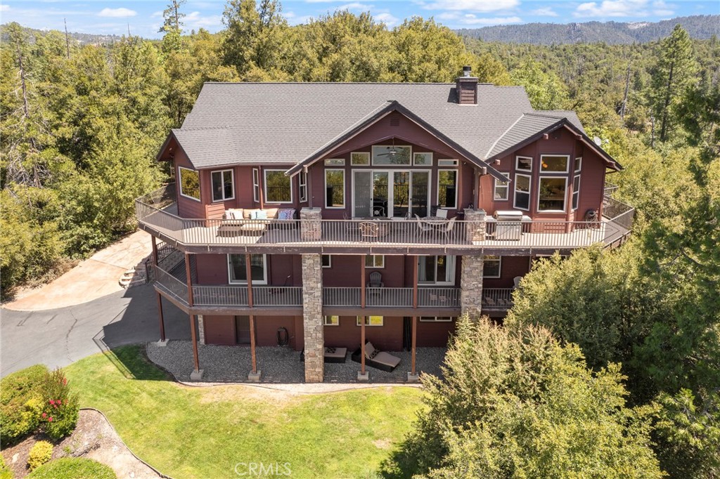 Elegant, custom home in the highly desirable Bass Lake Estates neighborhood. Terrific lake views from nearly every room, & 180 degree views from the wraparound deck. Paved, year round access to the oversized .89 acre parcel, covered in mature oak trees and a lovely rock formation just outside the rear windows. The kitchen features stainless steel appliances including a Jenn-Air stovetop, KitchenAid oven and microwave, and a handy built-in ice maker. The double stainless steel kitchen sink offers panoramic lake views. The spacious living area offers a woodburning fireplace for cooler evenings, knotty pine vaulted ceiling, and sliding glass door access to the outside living space, where you may relax to cooling lake breezes, convenient propane piped BBQ, and propane fire pit. After a day on the lake, each of the 6 bedrooms provides immediate access to either a private bathroom or Jack & Jill bath, each with a step-in shower. The primary suite has a private balcony, dual walk-in closets, step-in shower, and "jetted tub with a lake view". Central heat and dual zoned AC create year round comfort, and the home is conveniently hooked up to Campora propane, the Bass Lake Water Company, and Madera County sewer systems. This truly remarkable home is priced at a much lower price per square foot than other Bass Lake offerings, and is a successful short term rental property. Make this lovely home your own, and by next July 4th you'll be viewing the famous fireworks from your front deck!