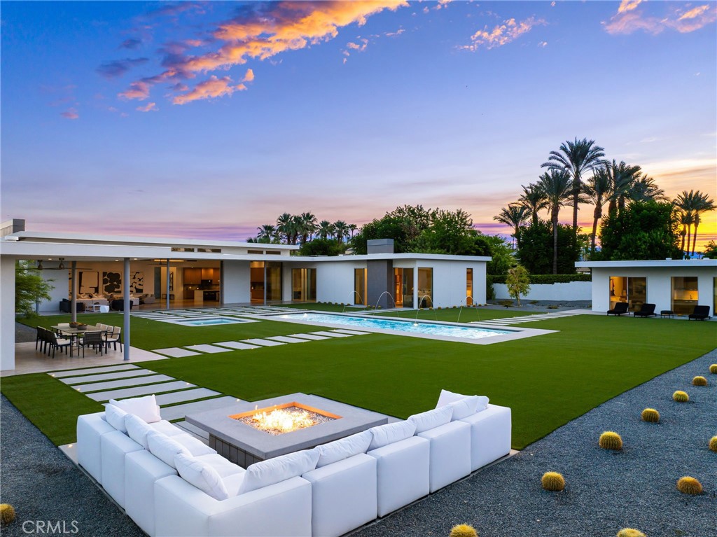 Set on a private 1-acre estate with south facing panoramic mountain views, new custom built 6,752 square foot residence blends luxury and mid-century with today’s most advanced technology and finishes. Enclosed behind 6-foot block walls and a wired security system, this property offers unmatched privacy. Entering through a 7ft wide 12ft tall custom pivot glass door, the great room opens to the outdoors with 40’ x 12’ automated pocketing glass walls, creating a seamless flow between living, dining, and entertaining. The chef’s kitchen is anchored by a 6.5 x 13 foot waterfall quartz island with seating for eight, dual dishwashers, commercial-grade Viking appliances, a custom vent hood, built-in espresso machine, and beverage station. Custom rift-sawn white oak cabinetry, imported Italian porcelain tile, and custom wide plank white oak engineered flooring elevate every detail. The main residence features 6,072 square feet, 5 bedrooms, 5 bathrooms, a formal powder room, temperature controlled wine cellar, including a primary suite with a private fireplace, floating dual vanities, Toto Neorest bidet, wet bar with wine fridge and its own climate zone and water heating system for ultimate comfort. A flexible bonus room offers endless possibilities—gym, office, or theater. The family room is designed for effortless entertaining, featuring a wet bar with dual refrigerators. The space has integrated surround sound. Extending the experience outdoors, the property is equipped with a whole-estate speaker system, including hidden speakers throughout the landscaping for seamless indoor-outdoor living. The spacious laundry room leads to the 4 car temperature controlled garage with epoxy flooring. Outdoors, a 500 sq. ft. entertainer’s cabana rivals any luxury resort with a full Viking kitchen, 36” barbecue with rotisserie, refrigerator, dishwasher, fireplace, TV, misting system, and full bath with outdoor shower. Entertain at the sparkling 40 foot pool with fountains, an app-controlled fire pit, and outdoor lounge areas complete the space. For guests, a detached 680 square foot casita provides a private oasis with a living area, bedroom, full bathroom, two high powered Mitsubishi AC units, kitchenette, and laundry. Every system in the home is designed for luxury: 5 Wi-Fi controlled HVAC zones, commercial-grade insulation, variable-zone cooling, tankless water heaters, concealed owned solar, custom lighting, surround sound, and whole-property misting and music systems.