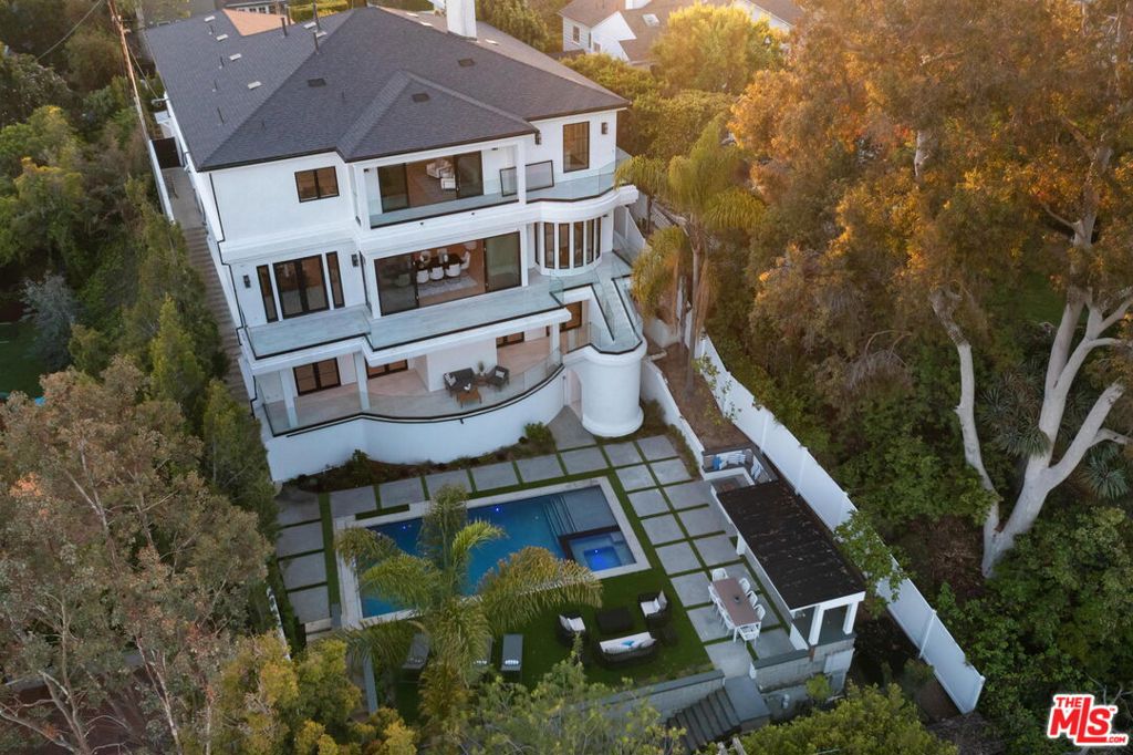 Located at the end of a desirable Brentwood cul de sac, this exclusive residence is highlighted by its lush setting, intricate architectural details, and uniquely-inspired amenities. Situated behind a gated facade, the three-story residence spans over 7,400 square feet, and includes five bedrooms and seven bathrooms, all featuring oversized windows and doors, encouraging an indoor/outdoor lifestyle. A contemporary open floor plan encompasses the main living room, dining room, and gourmet kitchen, equipped with chef-grade appliances, imported stone surfaces, and custom whitewashed cabinetry. Dedicated to entertaining, the spacious lower level of the home has been outfitted with a plush theater and deluxe wet bar, opening directly to the impressive pool with spa, green lawns, barbecue area, and built-in firepit. The secondary bedrooms and bathrooms are ideally situated throughout the home while the primary suite sits at the pinnacle of the residence and showcases an oversized custom marble slab shower, sunken tub, dual walk-in closets, and a private balcony allowing for every chance to take in the home's view. Additional features of the property include a luxe elevator, a Control4 smart-home system, a two-car garage, dual laundry rooms, and high-end finishes throughout.