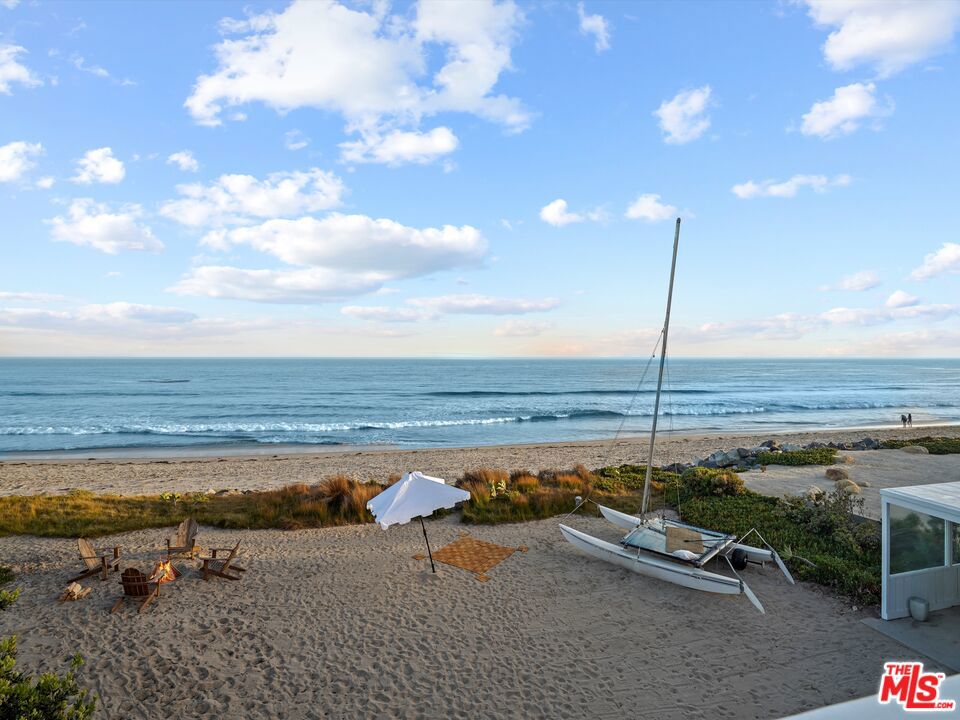 Seamless indoor-outdoor oceanfront living on spectacular Broad Beach means leisure, entertaining, and views, views, views. With approximately 73 feet of beach frontage, this private, gated beach home features mid-century styling, high plank-and-beam ceilings, floor-to-ceiling windows, abundant options for outdoor entertaining, plus a sensational upstairs primary suite. From the lovely, landscaped entry the home opens to a grand living/dining/kitchen space. Just beyond is a large partially covered patio for lounging and al fresco dining, the pristine expanse of Broad Beach, and the ever-changing panorama of ocean, islands, coastline, and sky. Lavish natural light illuminates the ocean-view kitchen, with butcher-block countertops, new appliances, and a breakfast bar. The exceedingly comfortable living room has a fireplace and the dining area is suitable for casual gatherings and sophisticated soires. Five of the home's six bedrooms are on the entry level. They include an ocean-view suite, an en-suite bedroom with a separate entrance currently being used as a gym/office, an additional beachfront bedroom, and an attached guest suite with a separate entrance. The primary suite presides over the entire second floor where it commands breathtaking whitewater views through enormous windows. It also features a large sun deck, a fireplace with a sitting area, and dual bathrooms. In addition to this classic Malibu beach home, the oceanfront property of approx. 0.65 acre has plans in process with the City of Malibu for a new approx. 4,170 square foot home with much of the underlying work completed, plus there are also plans and renderings for a Richard Landry-designed home of approx. 10,000 square feet.