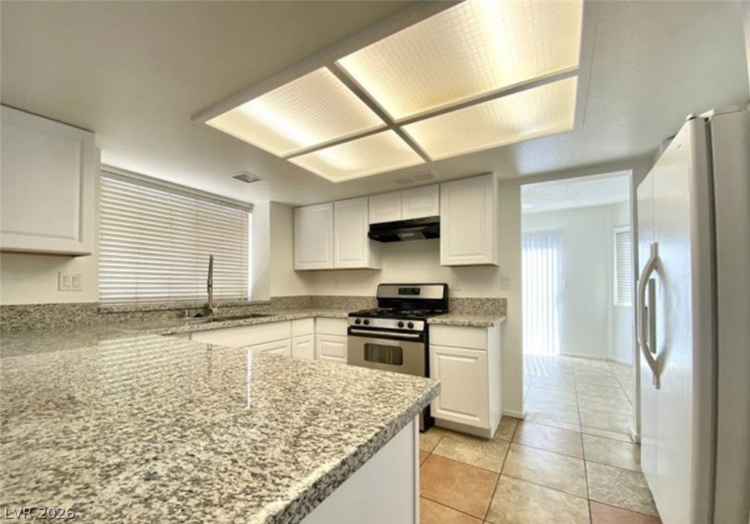Kitchen with white cabinets, white fridge with ice