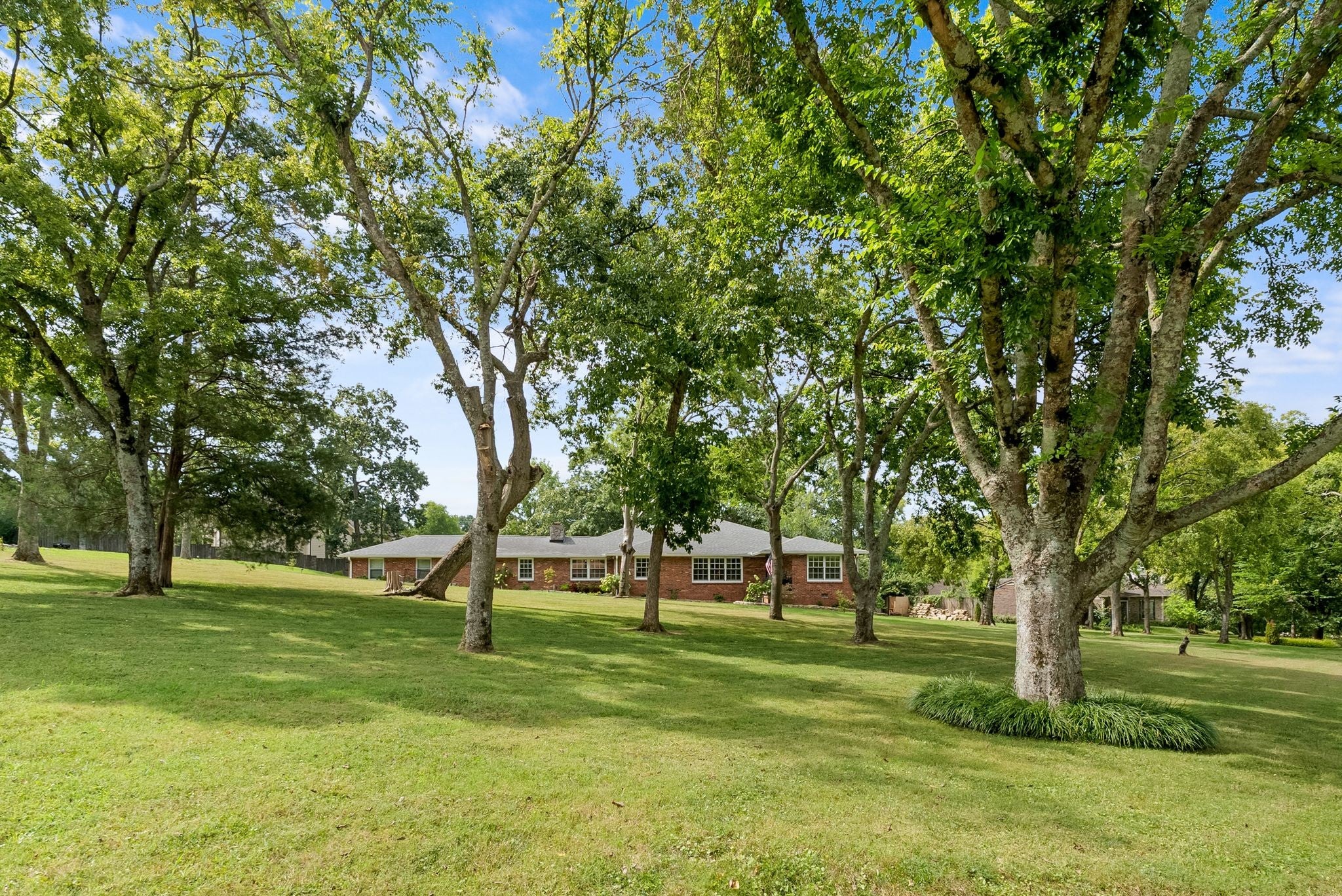 3-bed home for sale in Nashville, TN 37205, 615 W Meade Dr Lawn beneath mature shade trees with a single-story brick house set back at the far end of the yard