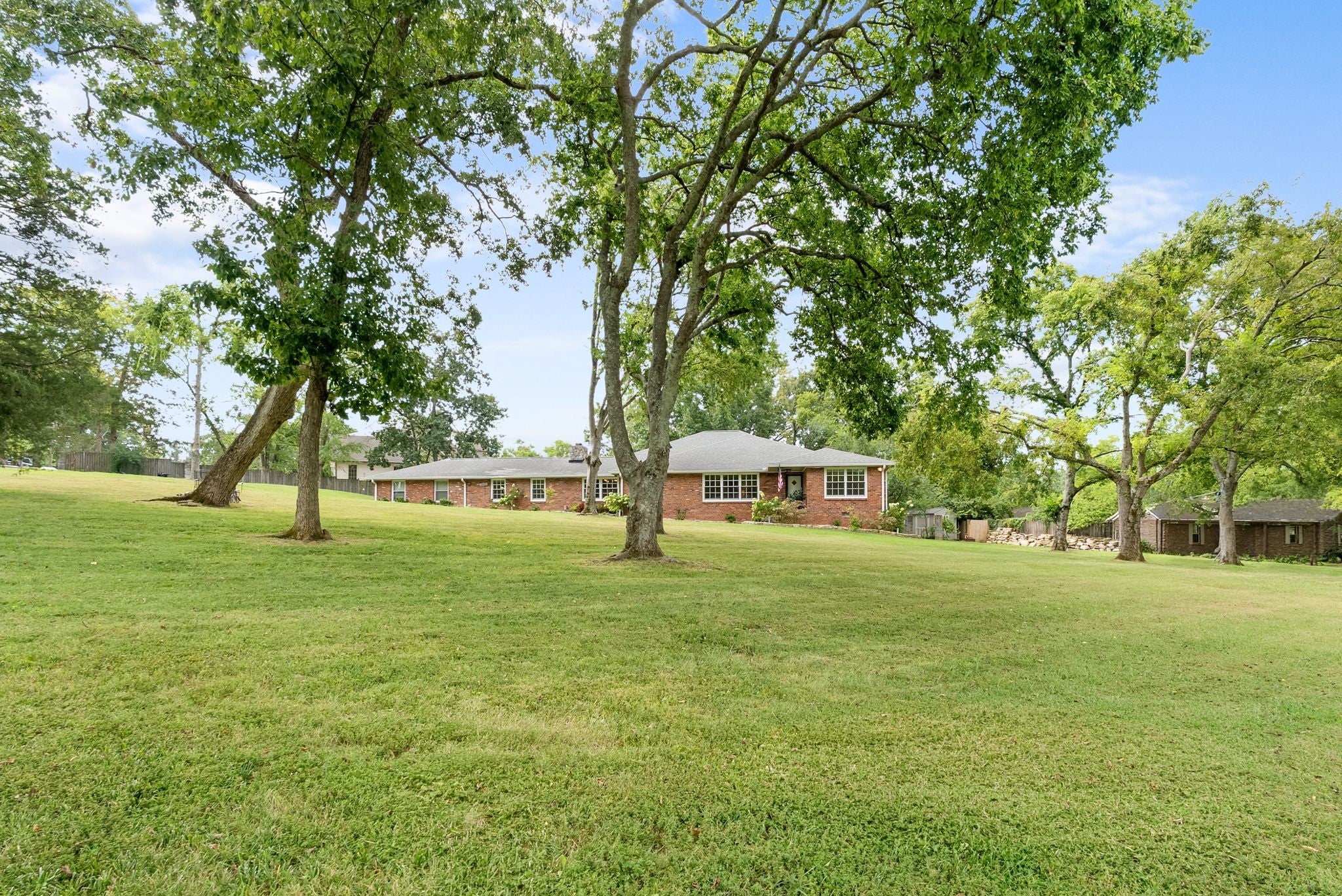 3-bed home for sale in Nashville, TN 37205, 615 W Meade Dr Brick house with white-trimmed windows set back across a lawn shaded by several tall trees