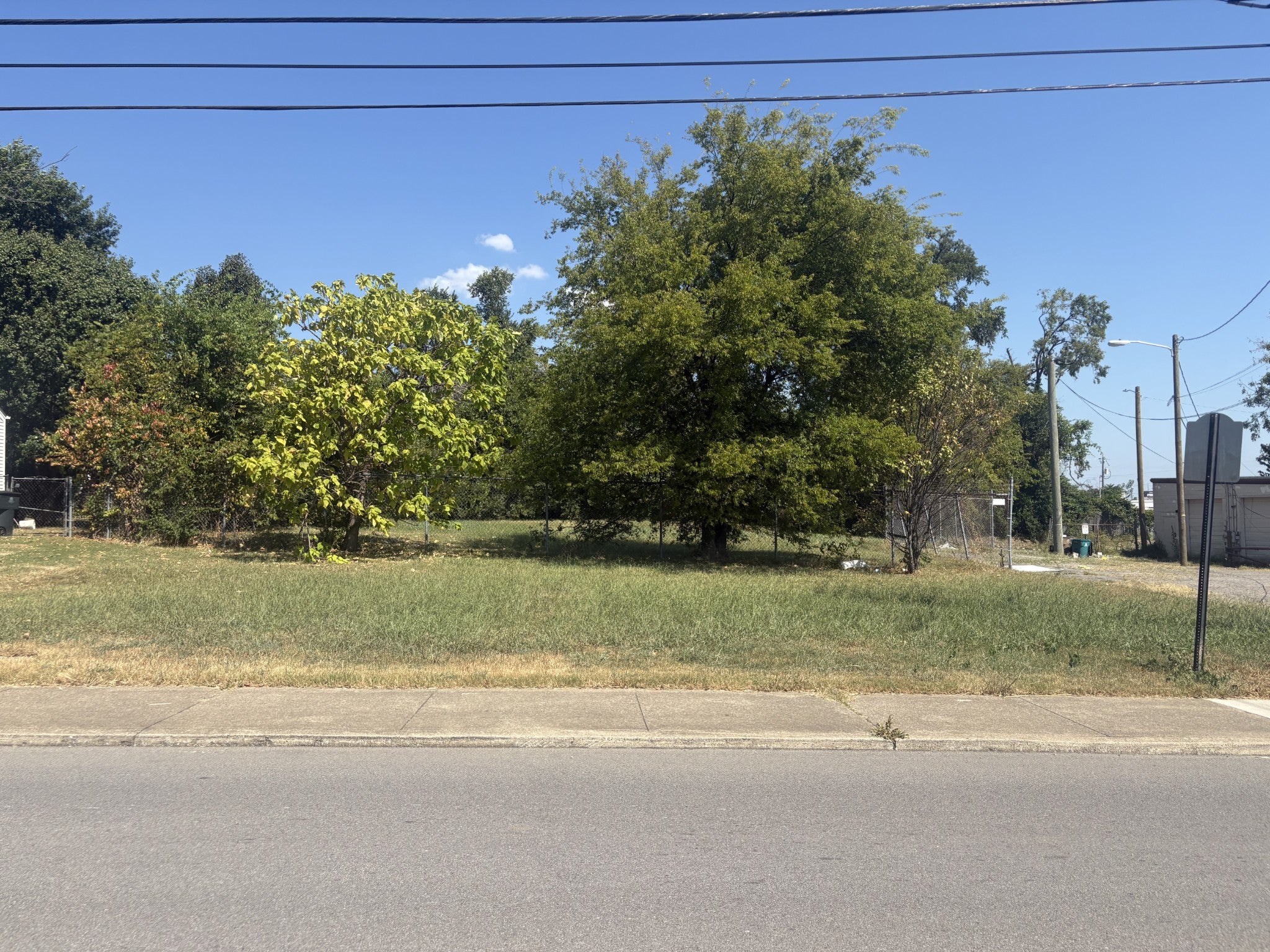 lot for sale in Nashville, TN 37216, 1019 Thomas Ave Grassy lot with several mature trees along the street frontage and a concrete sidewalk below