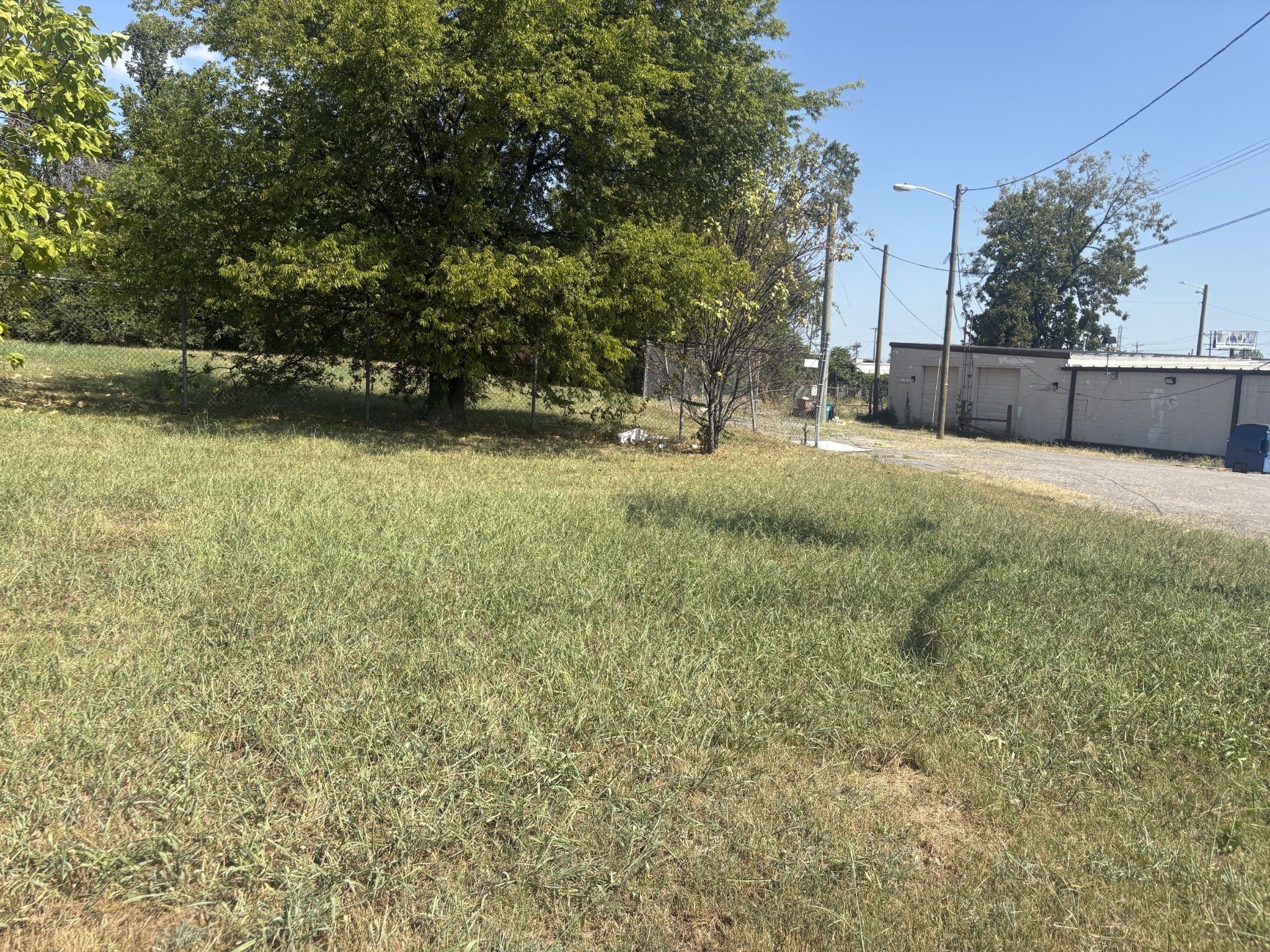 lot for sale in Nashville, TN 37216, 1019 Thomas Ave Lot looking toward a low commercial building with a gravel drive and utility poles at the right edge