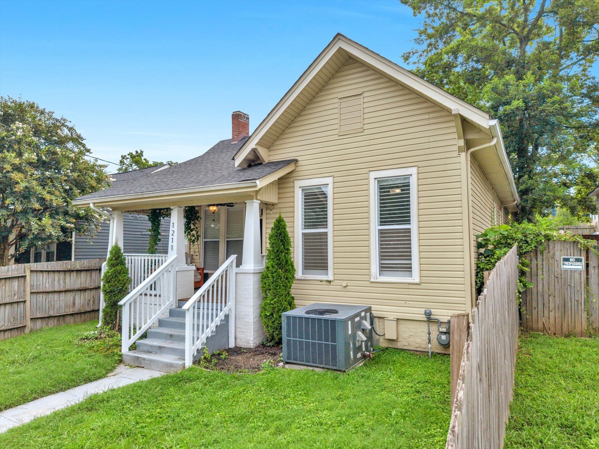 3-bed home for sale in Nashville, TN 37207, 1211 Stainback Ave Side view of a tan house with a gabled roof, a brick chimney, an outdoor air unit and a wood privacy fence