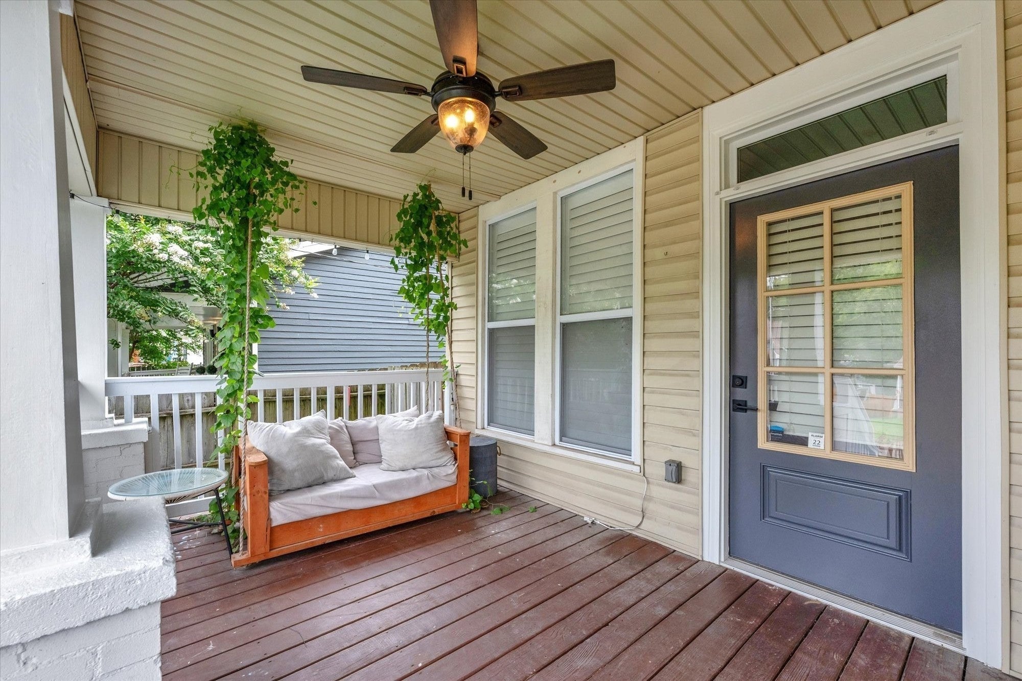 3-bed home for sale in Nashville, TN 37207, 1211 Stainback Ave Covered front porch with a wood plank floor, a porch swing with cushions, a ceiling fan and a dark blue door