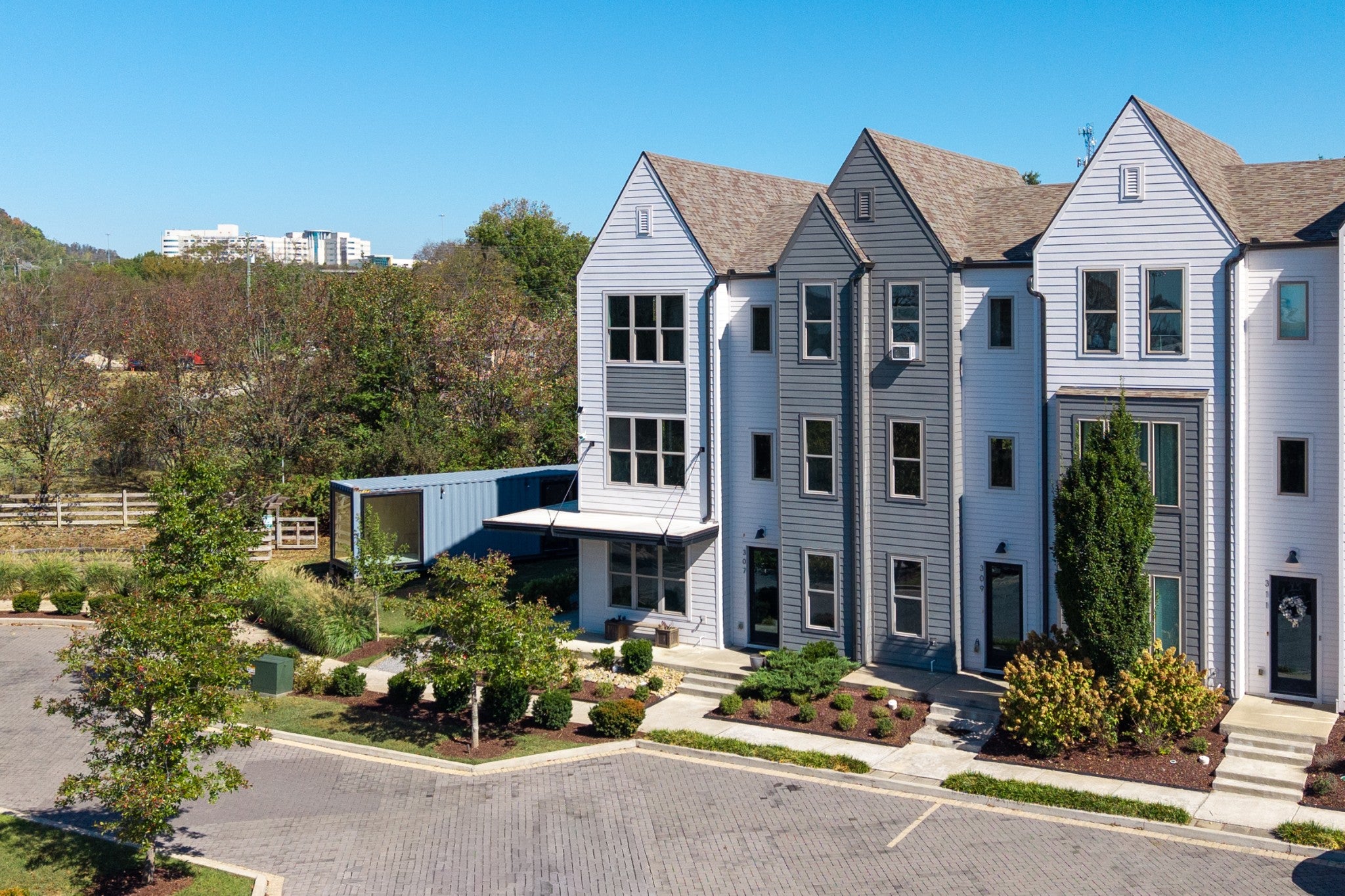 Townhome exterior with a covered front entry, a flat roof overhang over the lower level and a view of a pond and wooded hillside beyond