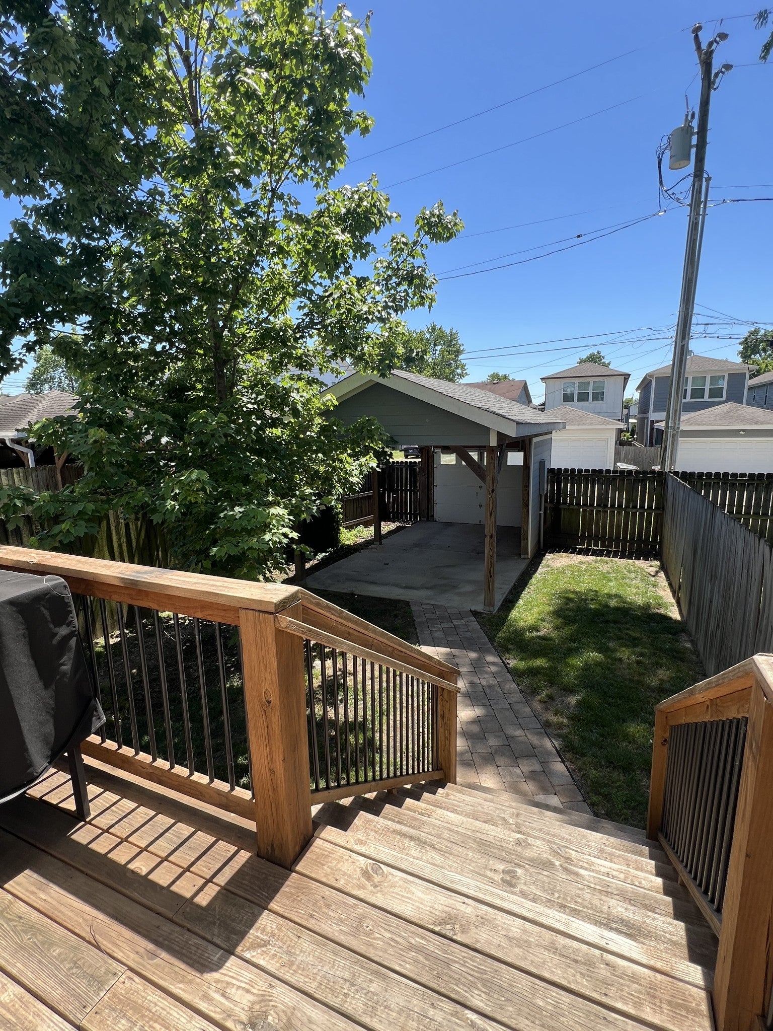 3-bed condo for sale in Nashville, TN 37209, 6205a New York Ave Wood deck with metal railing overlooking a back yard with a covered carport, a paver path and a wood privacy fence