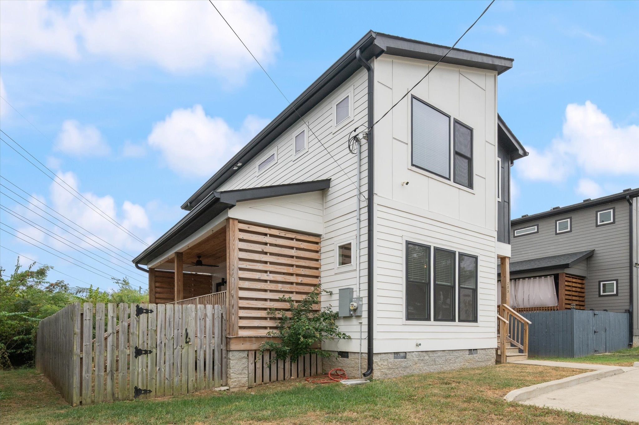 3-bed home for sale in Nashville, TN 37211, 203 Eisenhower Drive Side view of the home showing white siding, a covered porch with wood slat screening and a wood privacy fence along the side yard