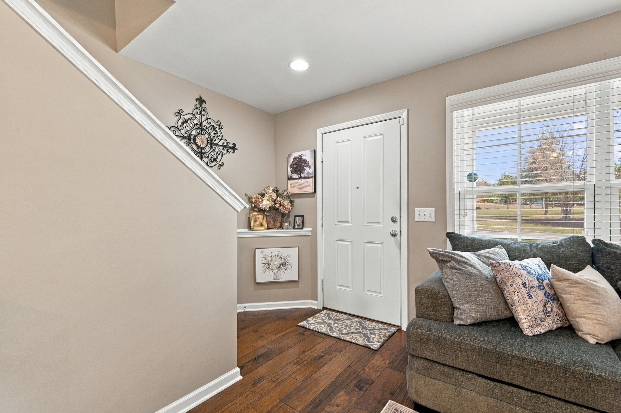 Entryway with wood-look floors, a white front door, a staircase on the left and a window with blinds