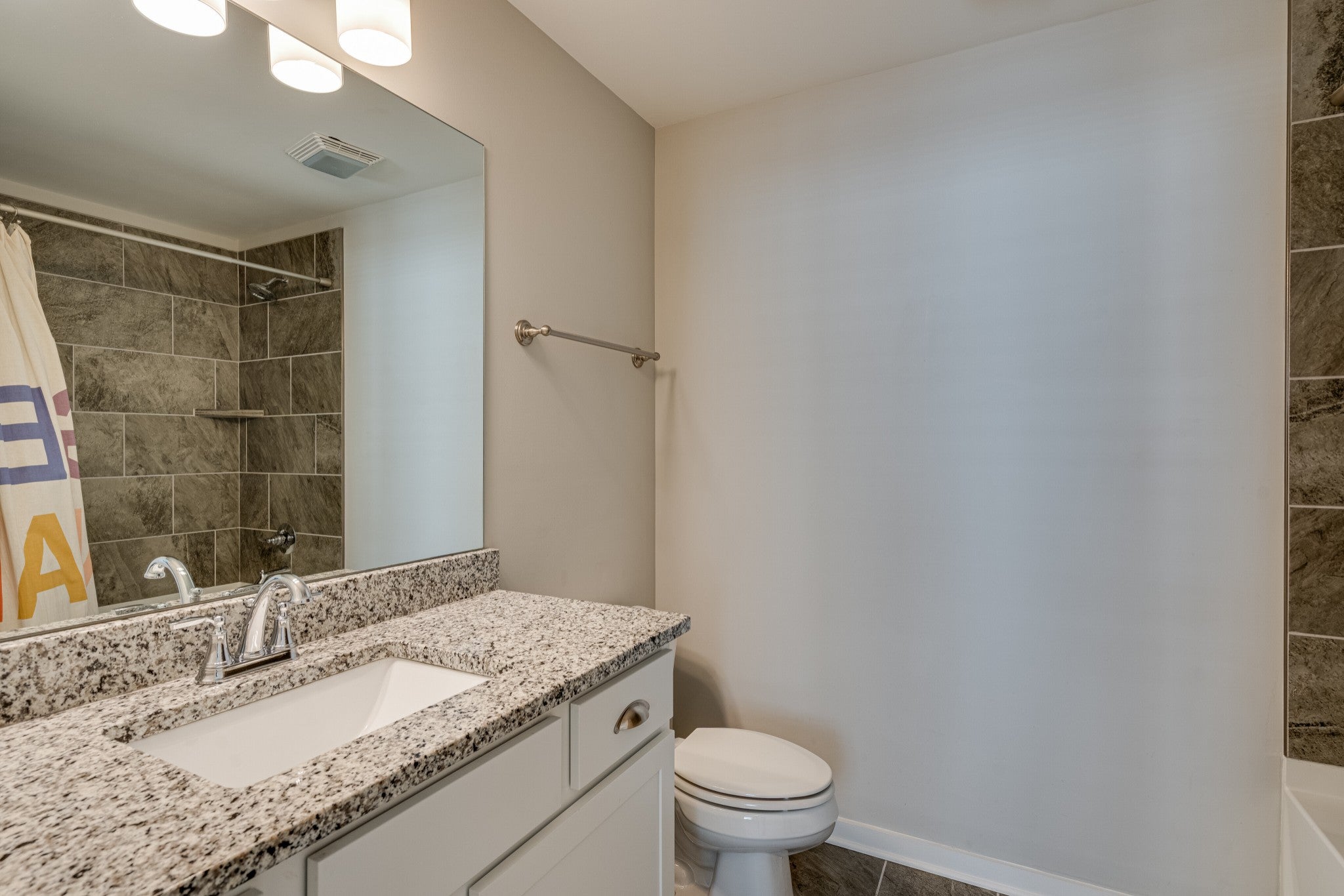 Bathroom with a tiled tub surround, a vanity with a light stone countertop and a single undermount sink