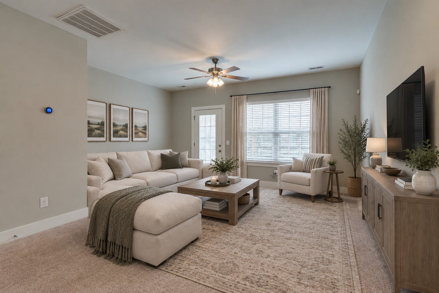 Living room with a sectional sofa, a ceiling fan, a tall window with blinds and an entry door with a glass upper panel