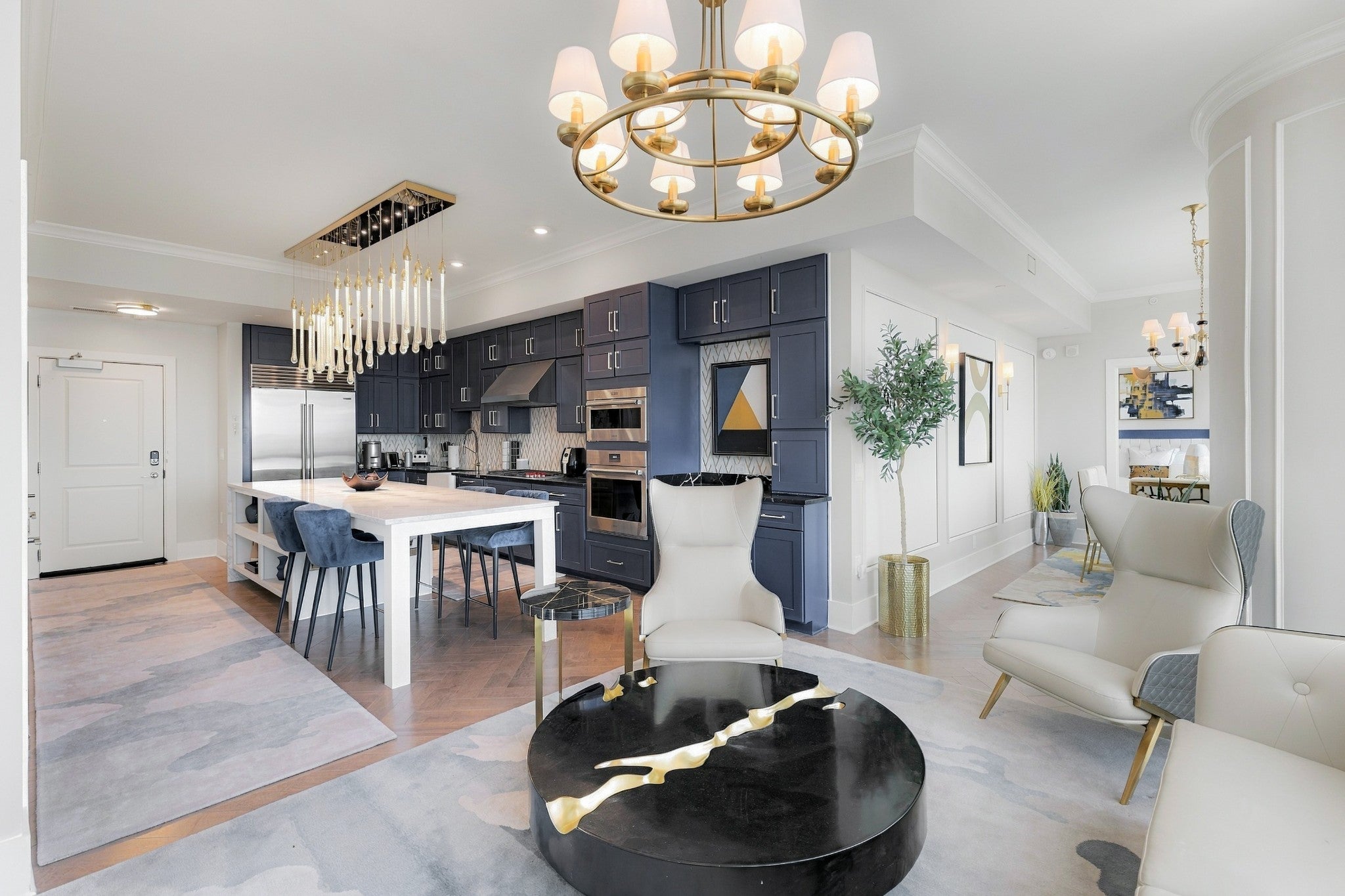 2-bed condo for sale in Nashville, TN 37203, 1616 West End Ave 3001 Open kitchen with navy cabinets, a white island with stools, stainless appliances and a gold chandelier