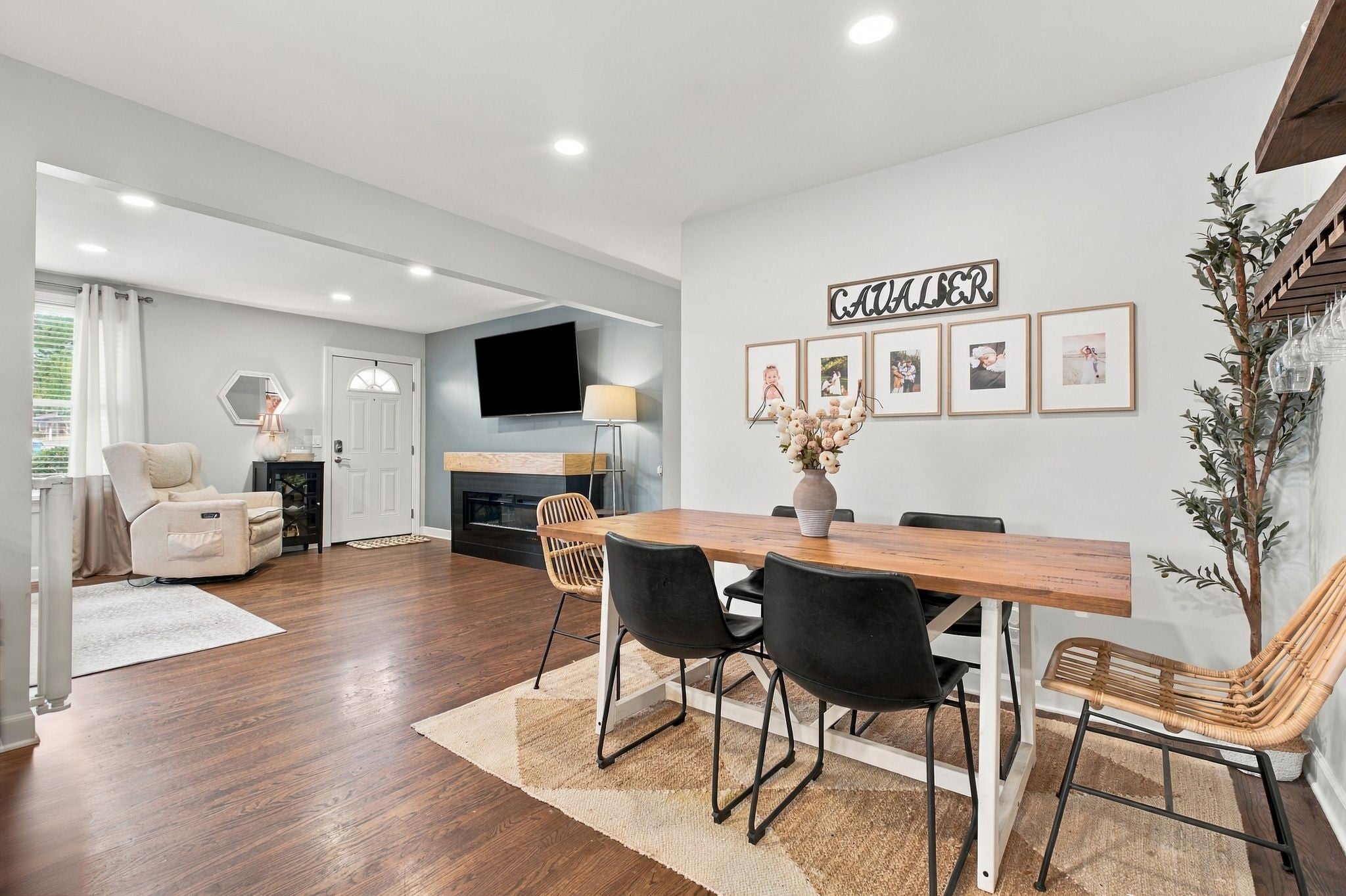 3-bed home for sale in Nashville, TN 37211, 613 Tobylynn Dr Dining area with a wood table, black chairs and a woven rug, open to a living room with a fireplace and wall-mounted television
