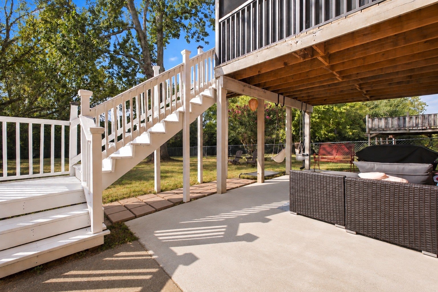 3-bed home for sale in Nashville, TN 37211, 613 Tobylynn Dr Covered outdoor area with a wood staircase leading down to a concrete patio, wicker seating and a fenced yard beyond