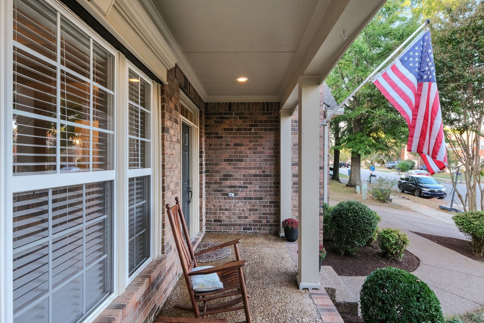 5-bed home for sale in Franklin, TN 37064, 403 William Wallace Dr Covered porch with a wooden rocking chair beside a row of double-hung windows with white shutters and brick walls