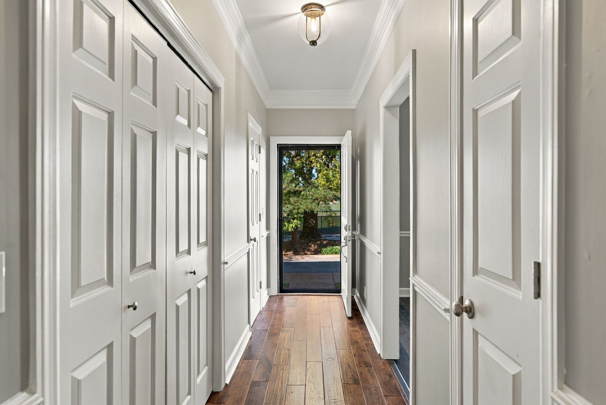 2-bed condo for sale in Franklin, TN 37064, 609 Boyd Mill Ave 15 Hallway with white paneled doors, crown molding, wood-look flooring and a glass front door at the end